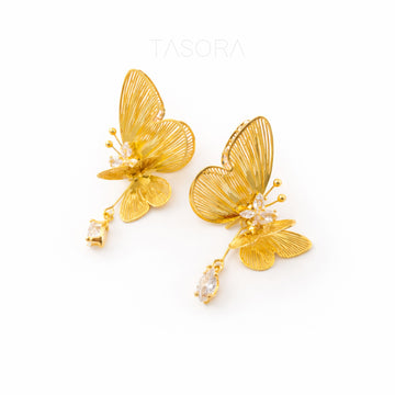 Gold butterfly earrings with a clear gemstone on a white background, branded 'TASORA'.