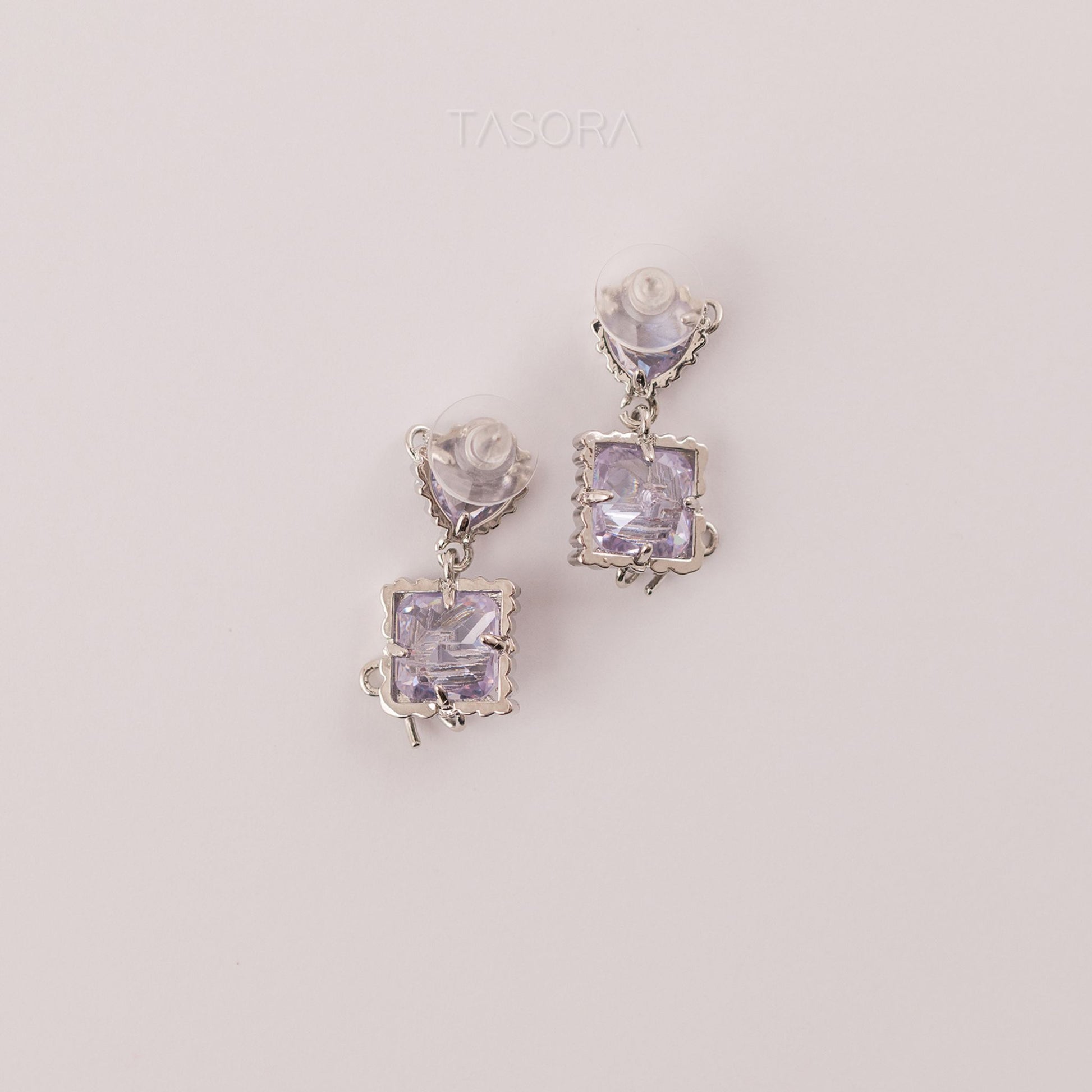 Back side of Bow Belle silver earrings with purple gemstones on a light gray background with TASORA branding