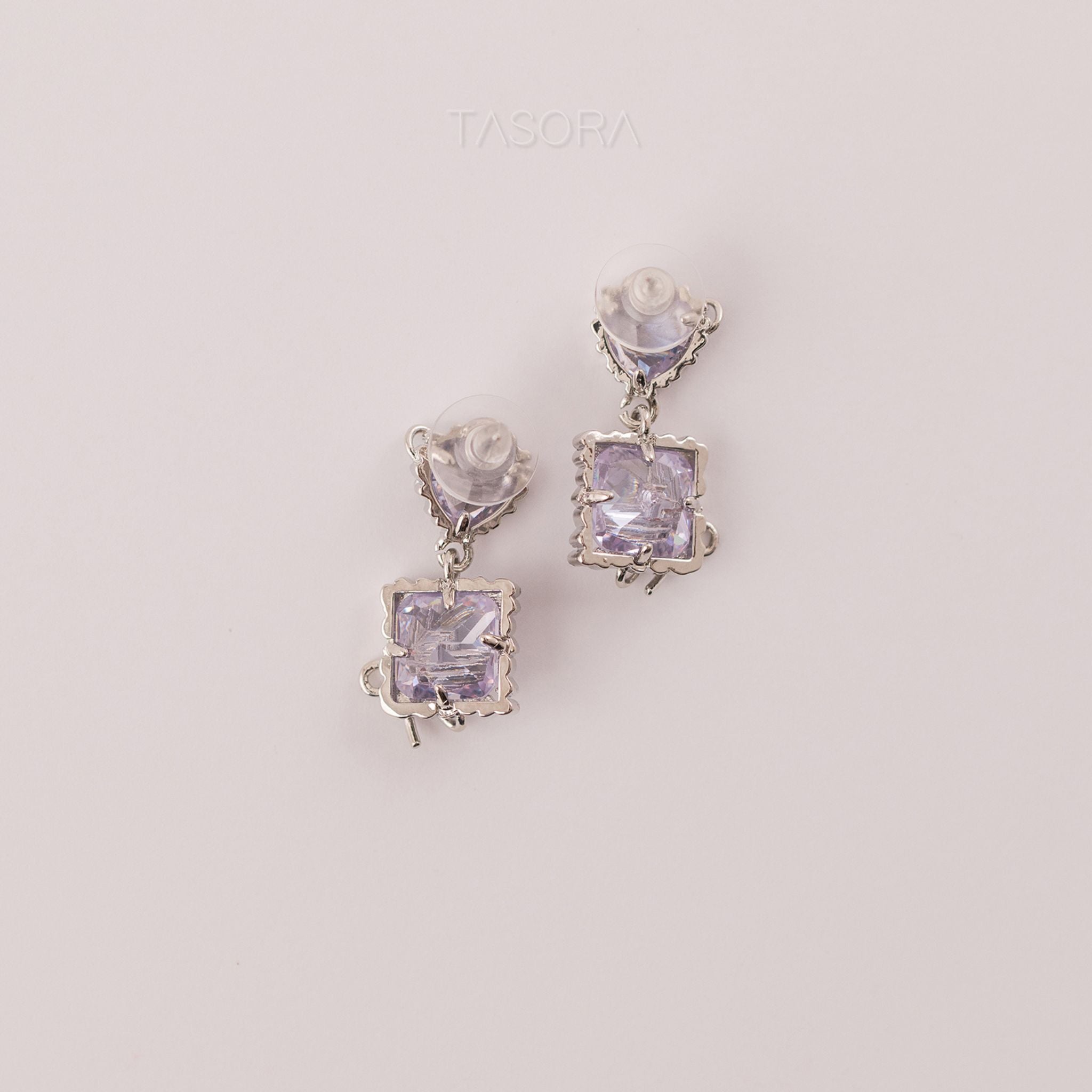 Back side of Bow Belle silver earrings with purple gemstones on a light gray background with TASORA branding