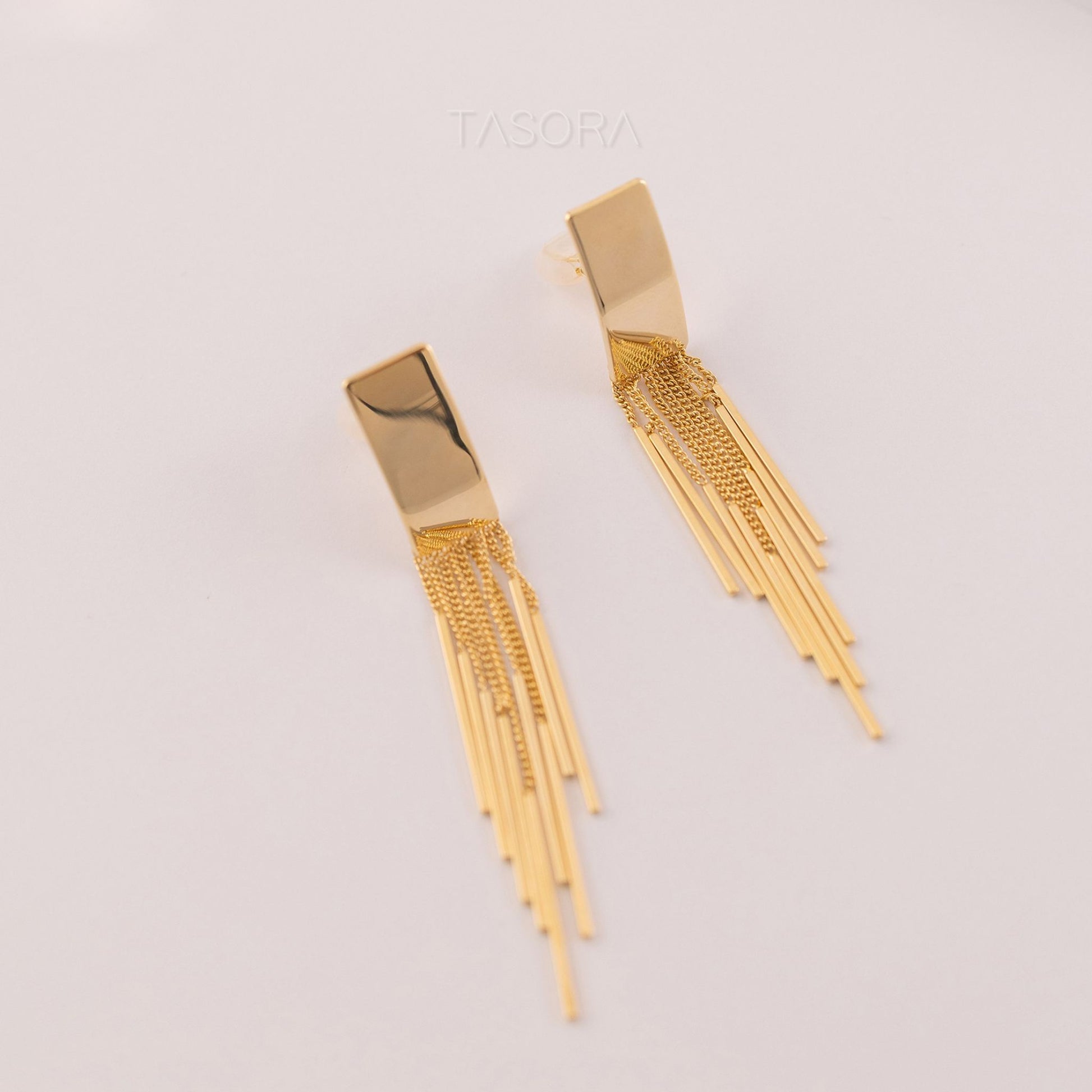 Cascade Flow golden earrings on a light background with 'TASORA' branding.