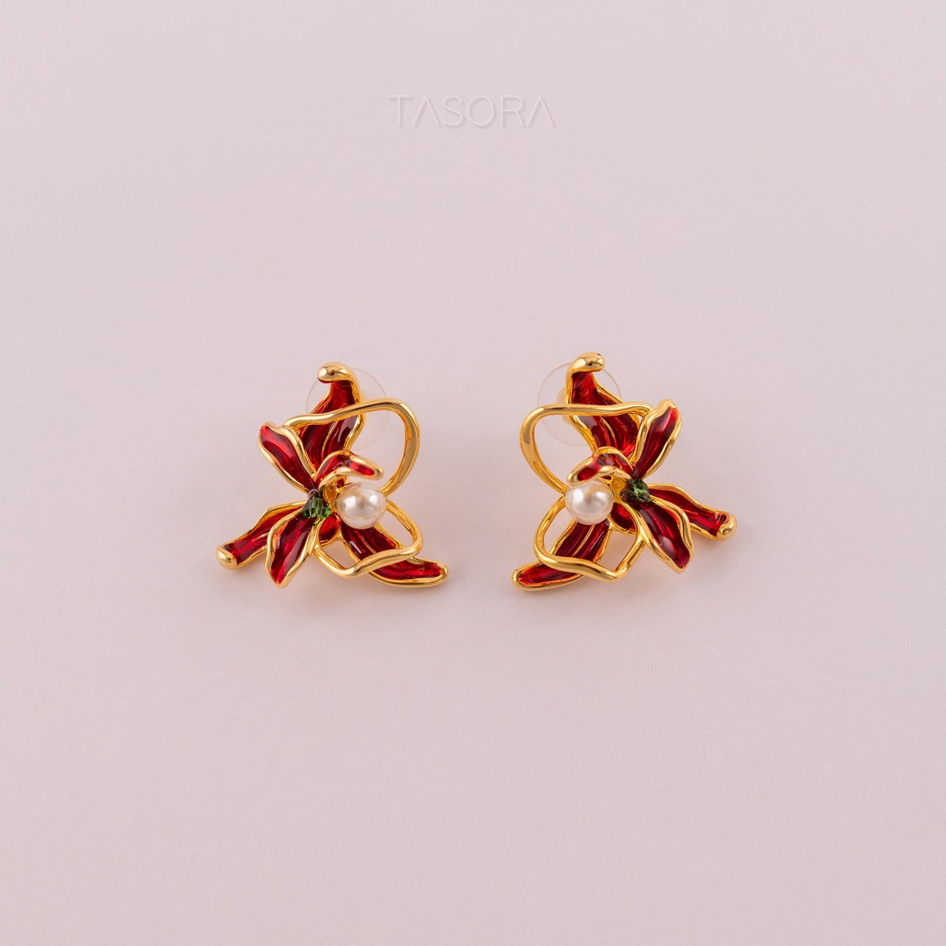 Pair of golden and red Dancing Flamenco Crimson earrings with pearls on a light pink background with TASORA branding