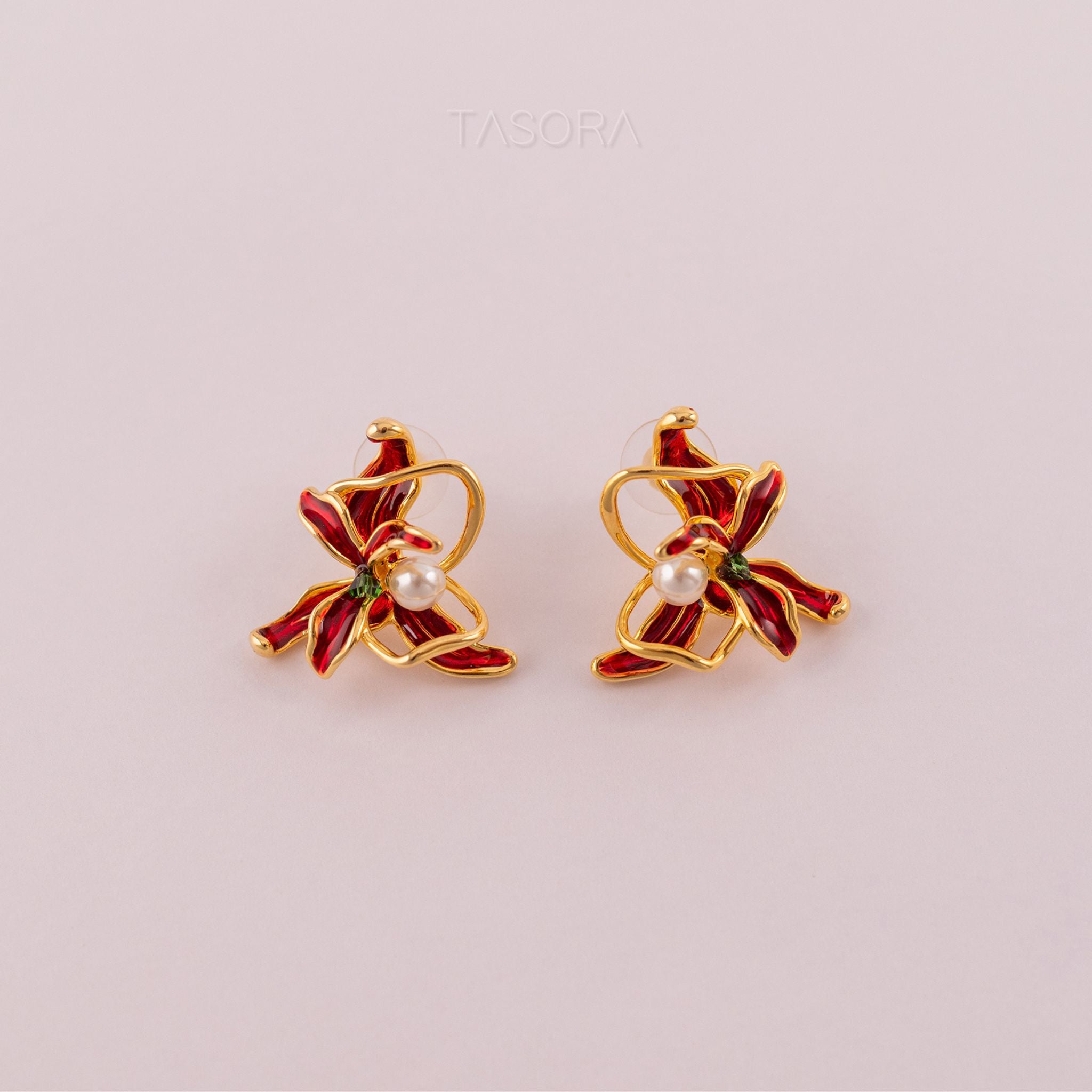 Pair of golden and red Dancing Flamenco Crimson earrings with pearls on a light pink background with TASORA branding
