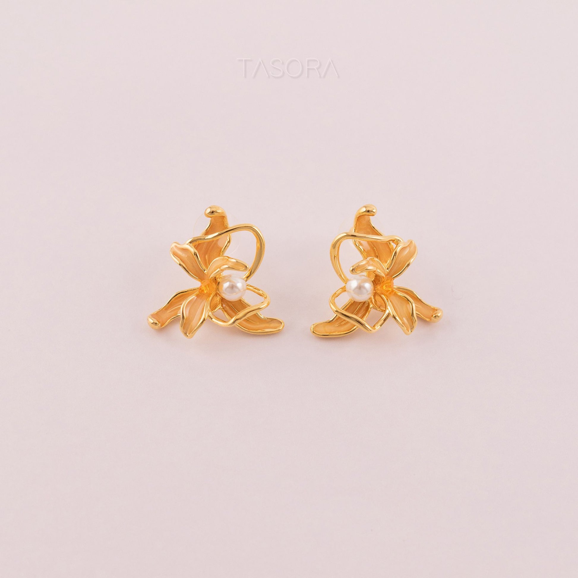 Dancing Flamenco Golden earrings with pearl centers on a light pink background, featuring the brand 'TASORA'.