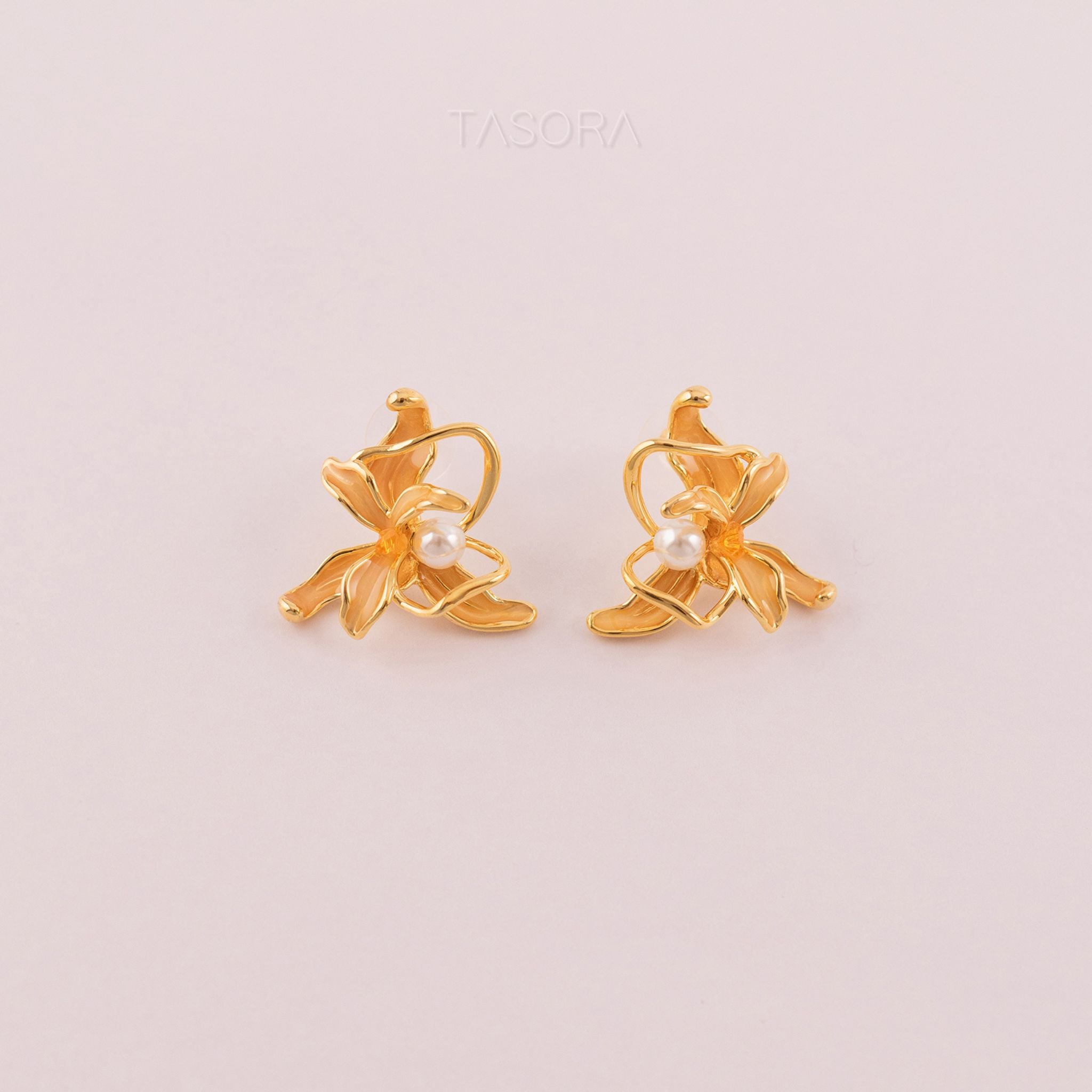 Dancing Flamenco Golden earrings with pearl centers on a light pink background, featuring the brand 'TASORA'.
