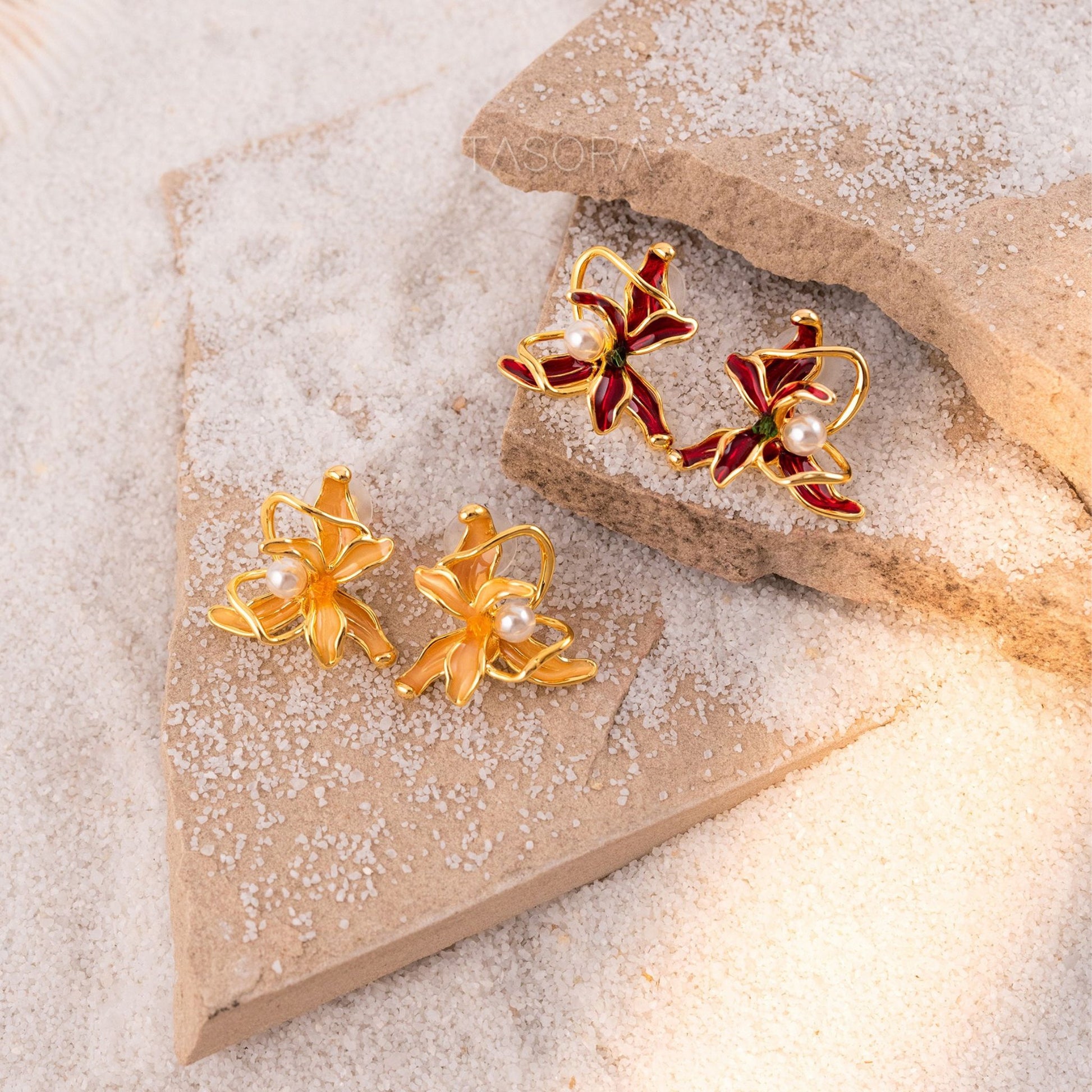Pairs of gold and red Dancing Flamenco earrings on a textured beige stone with TASORA branding