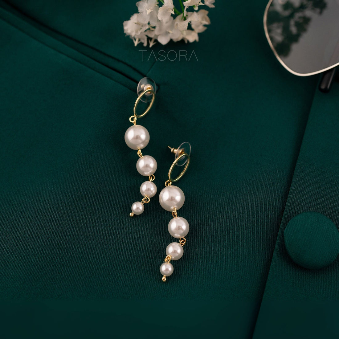 Dewy Pearl earrings on a dark green surface with 'TASORA' branding.