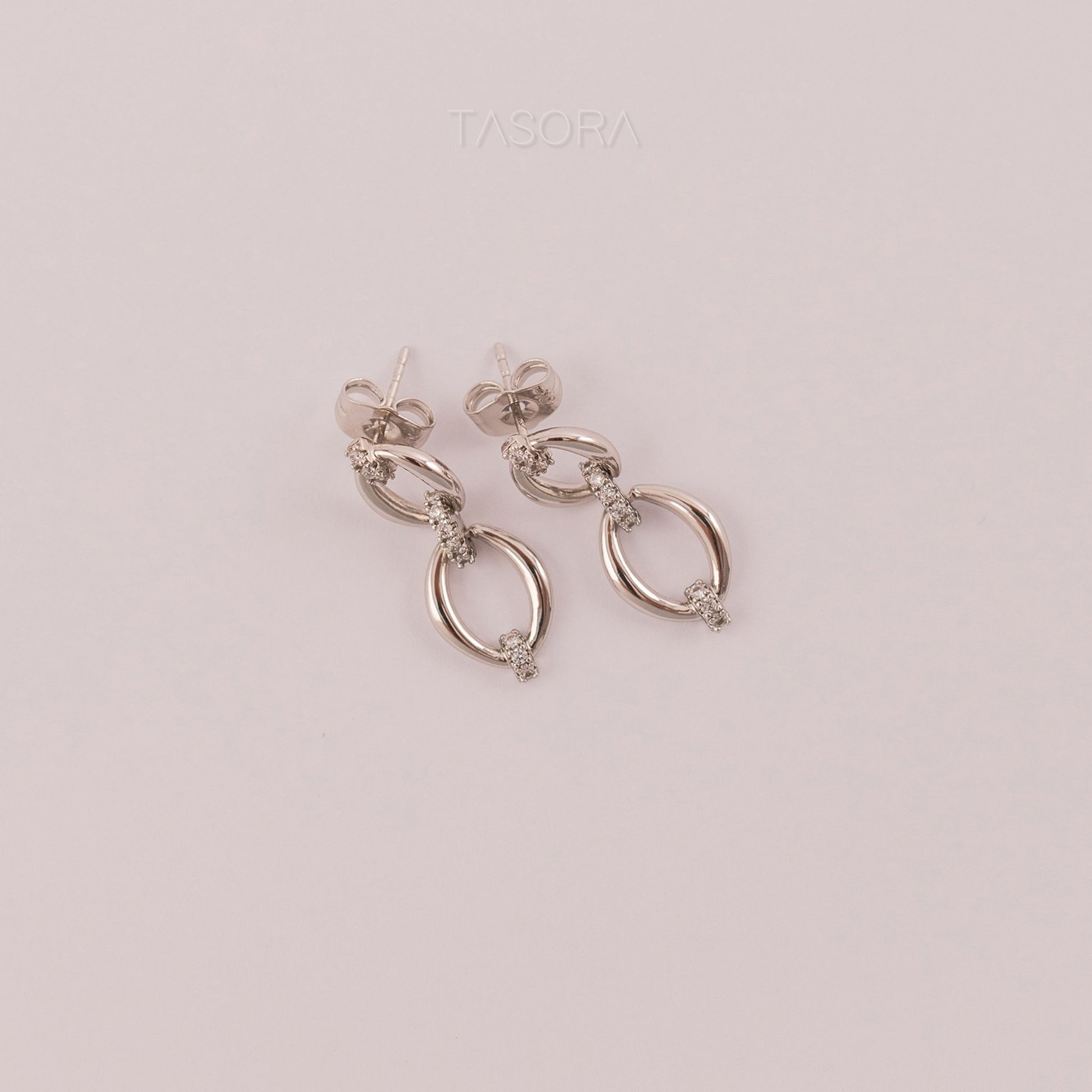 Elior Silver earrings on a light pink background with 'TASORA' branding.