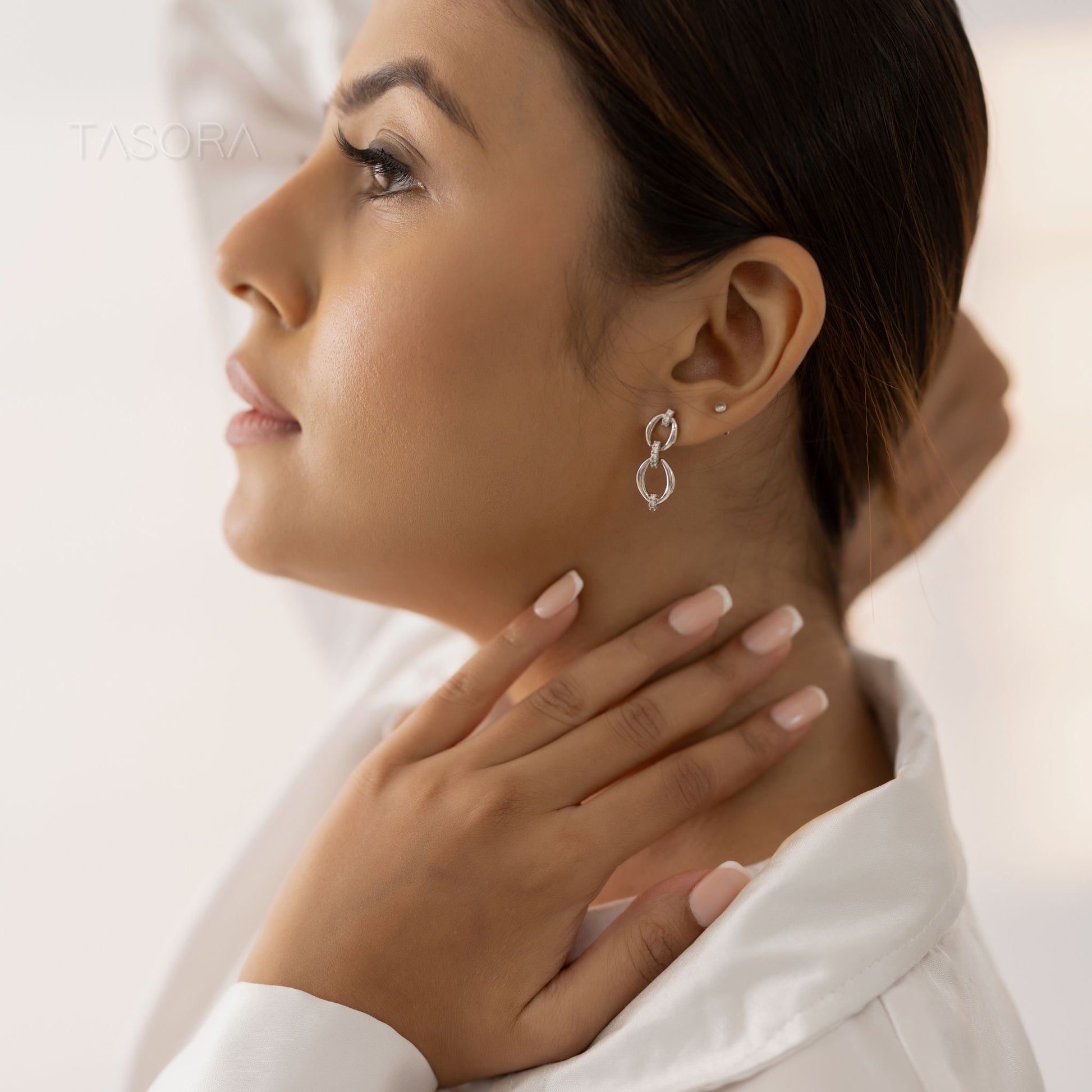 Woman wearing a TASORA Elior silver earring with a blurred background