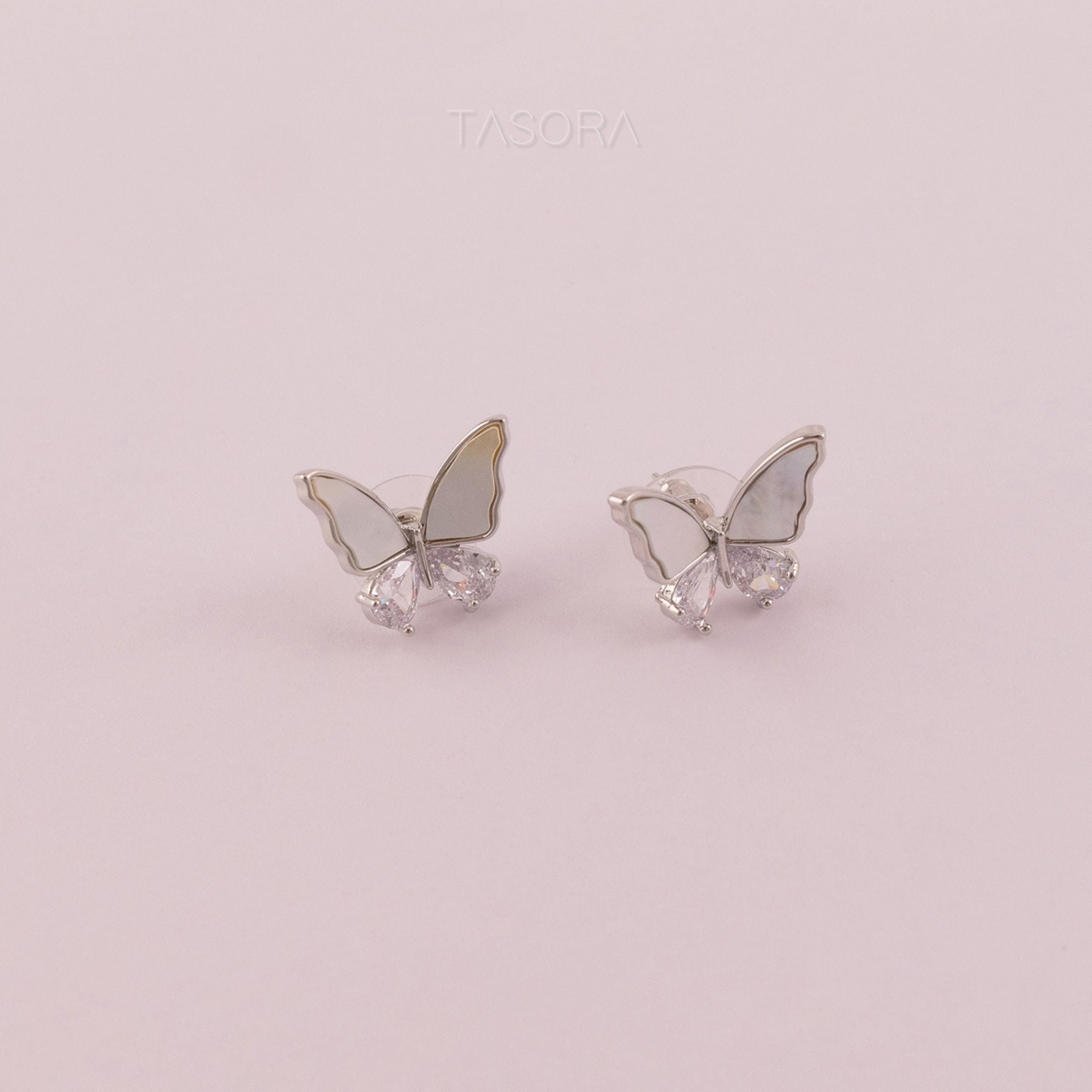 Butterfly-shaped Flutter wings silver earrings with gemstones on a light pink background with TASORA branding