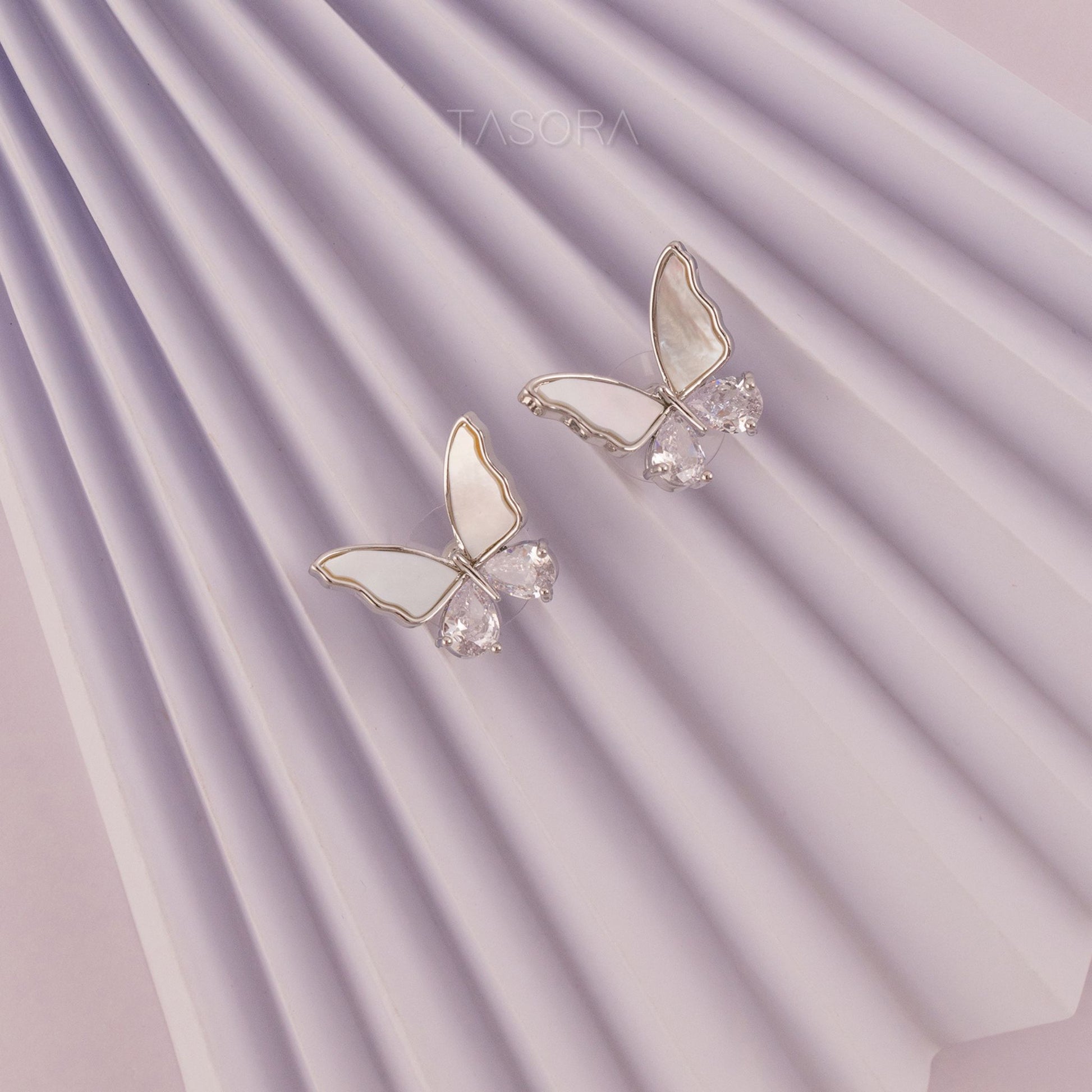 Butterfly-shaped Flutter wings silver earrings on a white, purple textured paper background TASORA branding