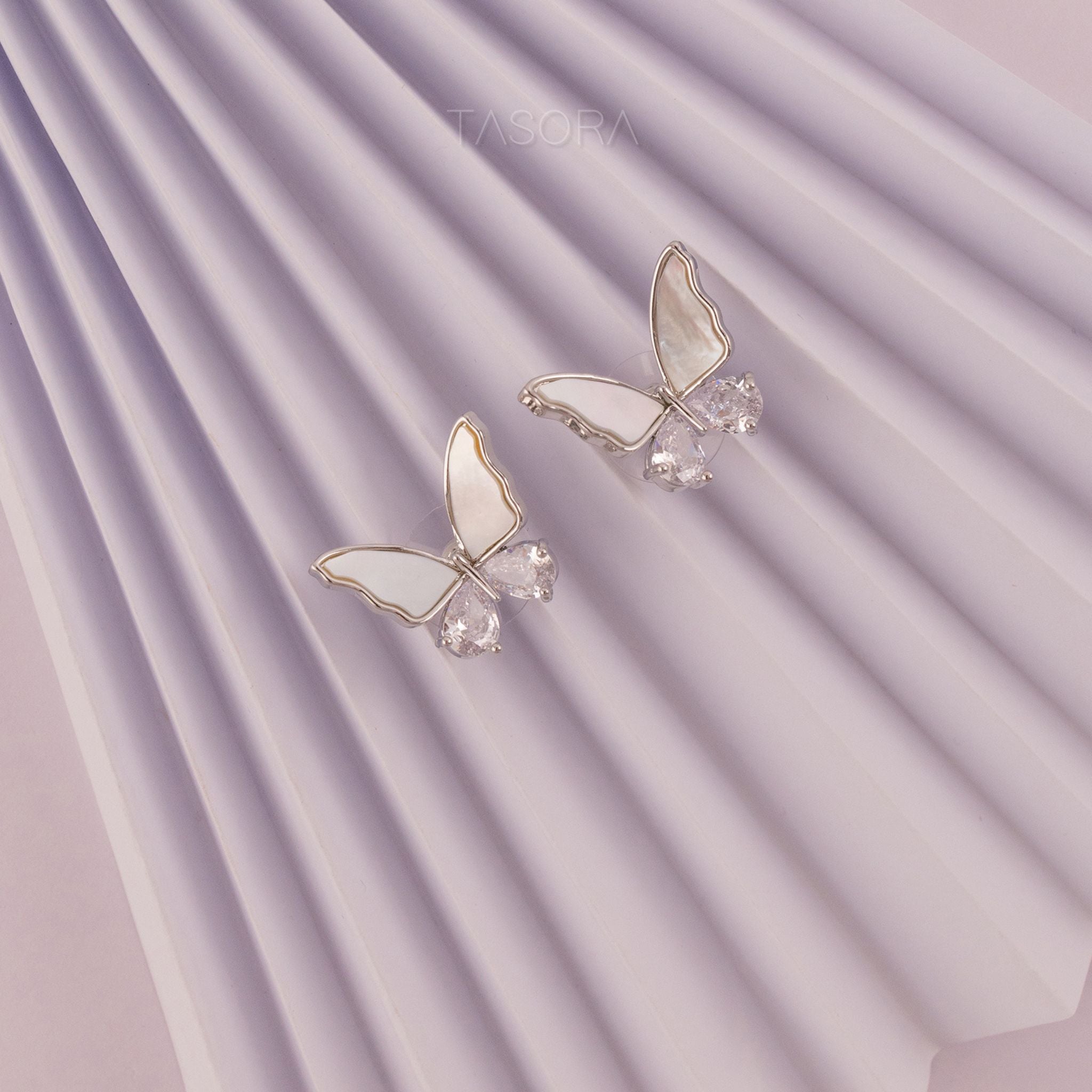 Butterfly-shaped Flutter wings silver earrings on a white, purple textured paper background TASORA branding