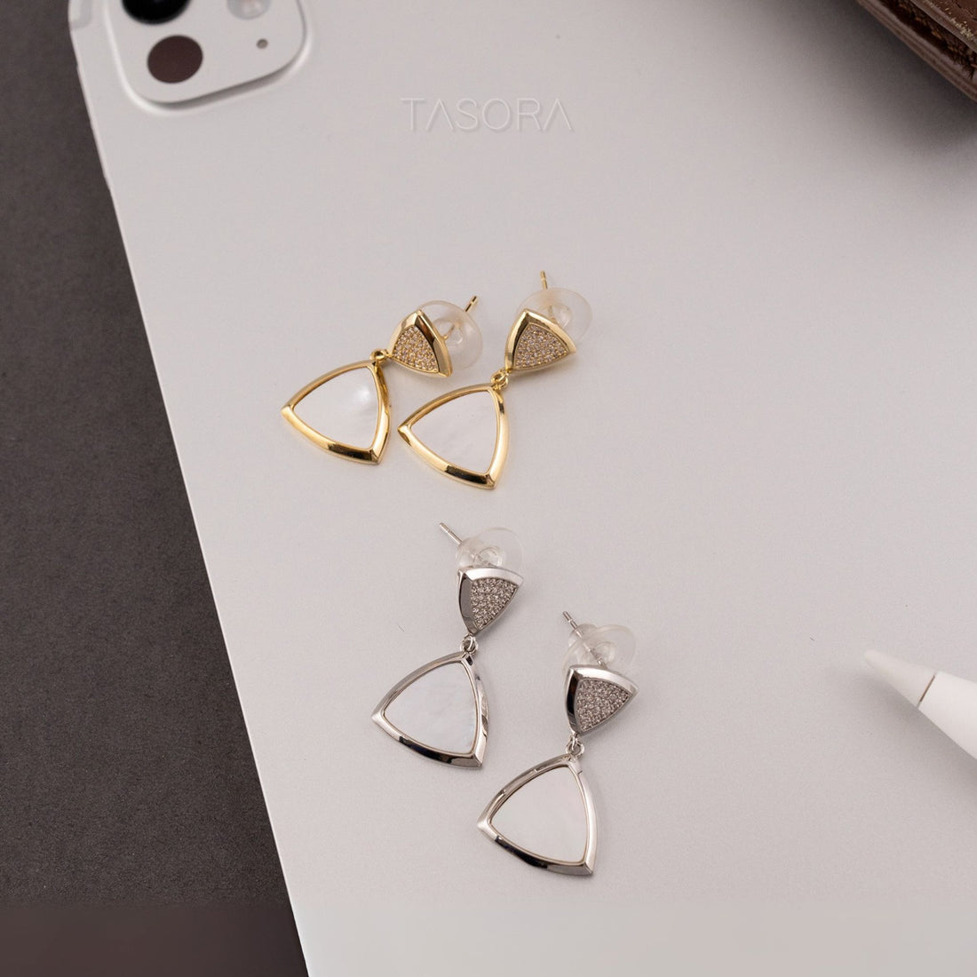Golden and silver triangle-shaped Gleamlet earrings on a light gray surface with 'TASORA' branding.