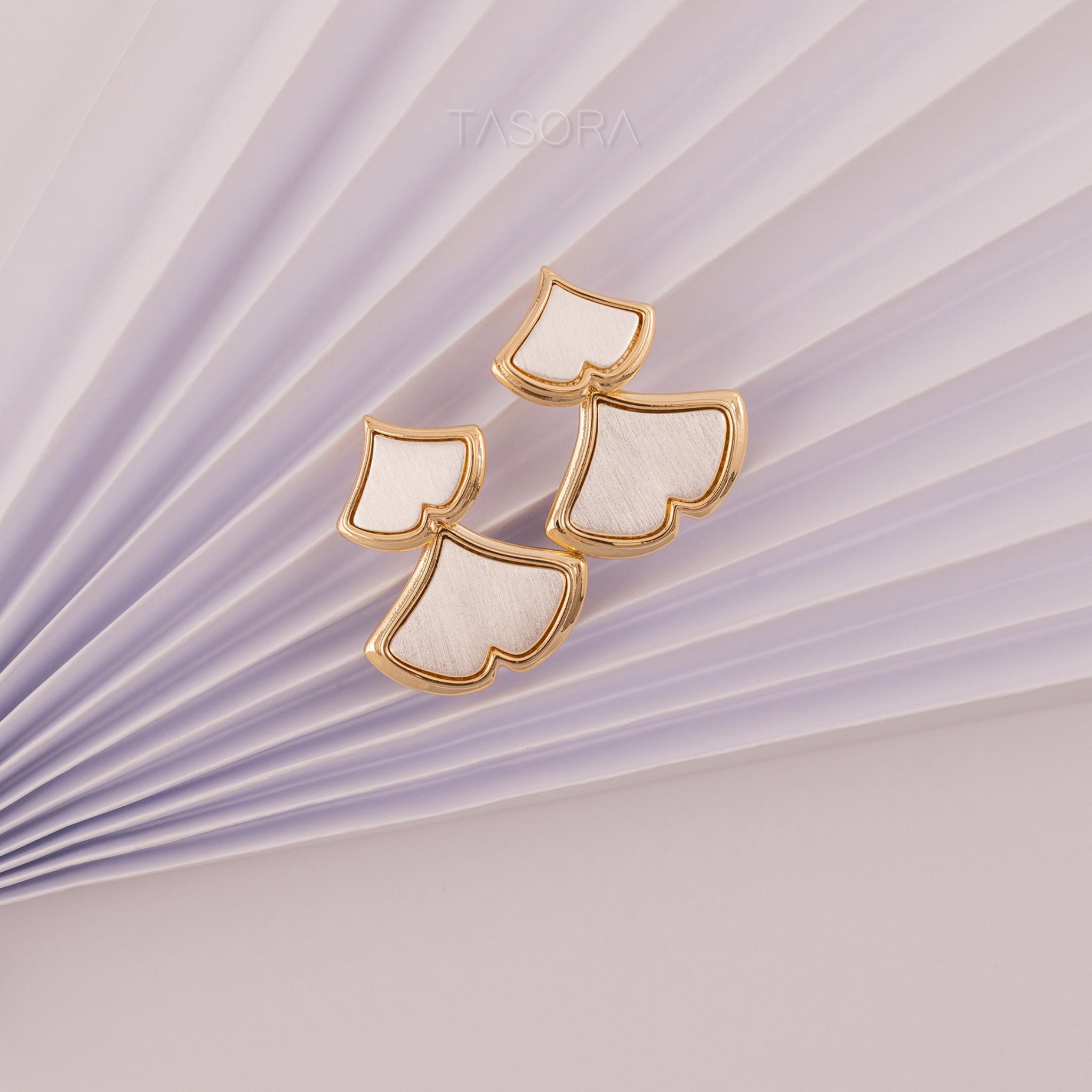 Pair of Golden Glint gold and white earrings on a textured paper background