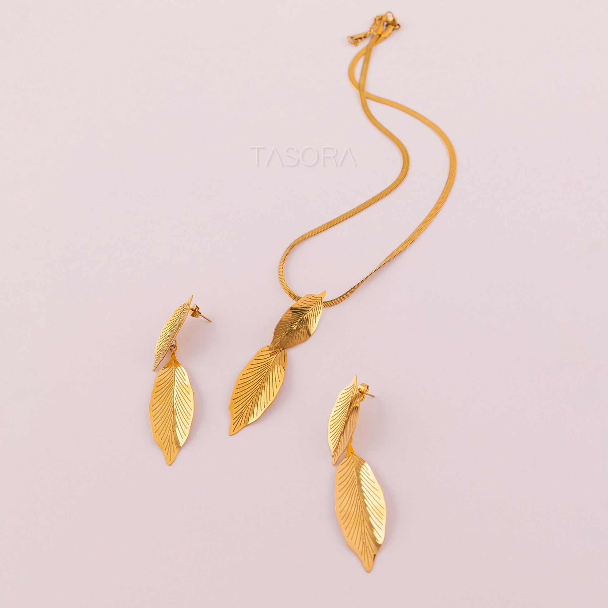 Golden Lustre Leaf necklace and earrings set on a light pink background with TASORA branding