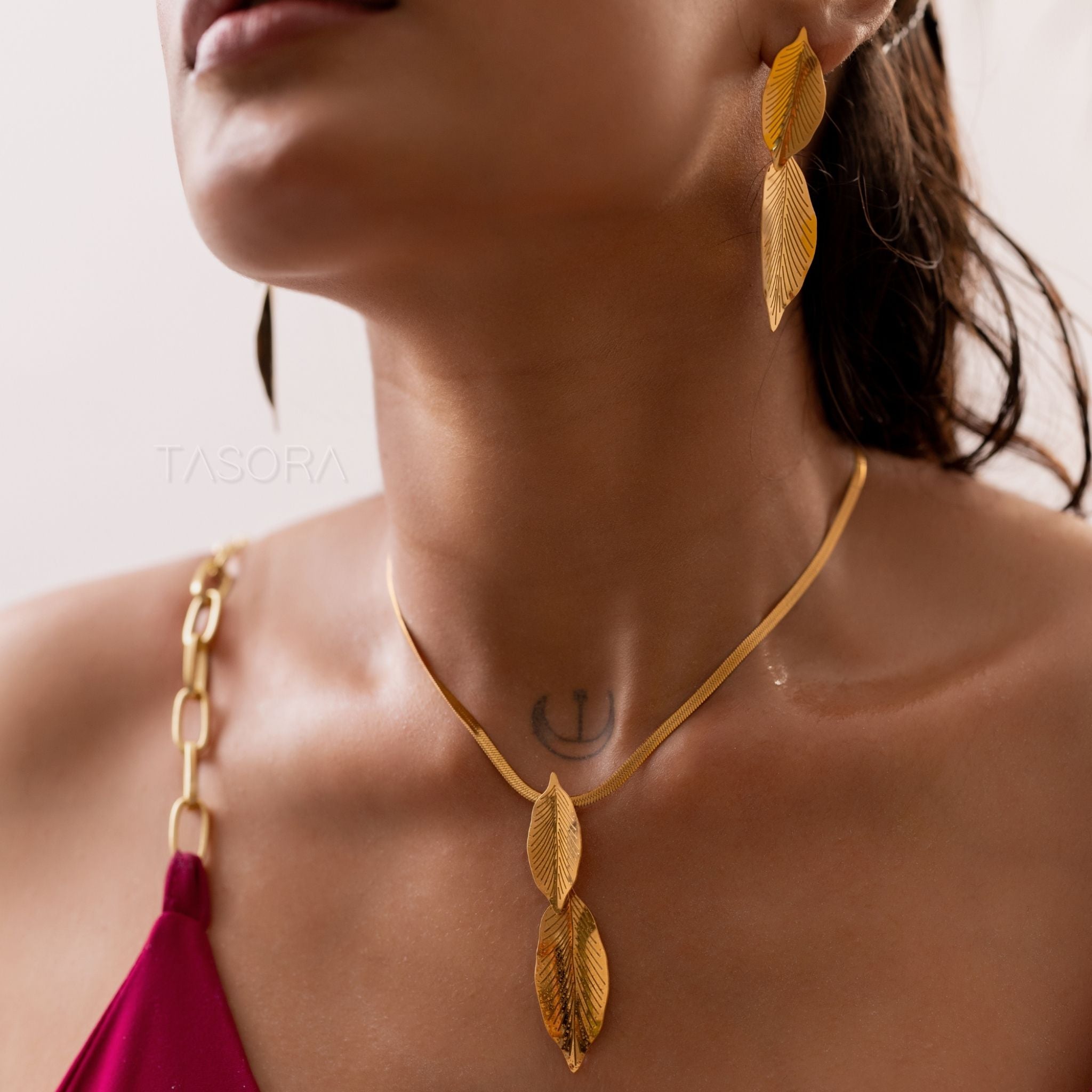 woman wear Lustre Leaf necklace and earrings of TASORA brand with a blurred background
