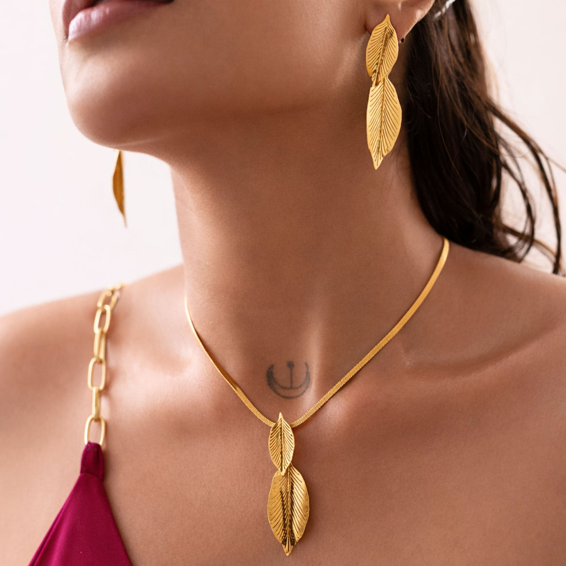 Gold leaf necklace and earrings on a model with a blurred background brand TASORA