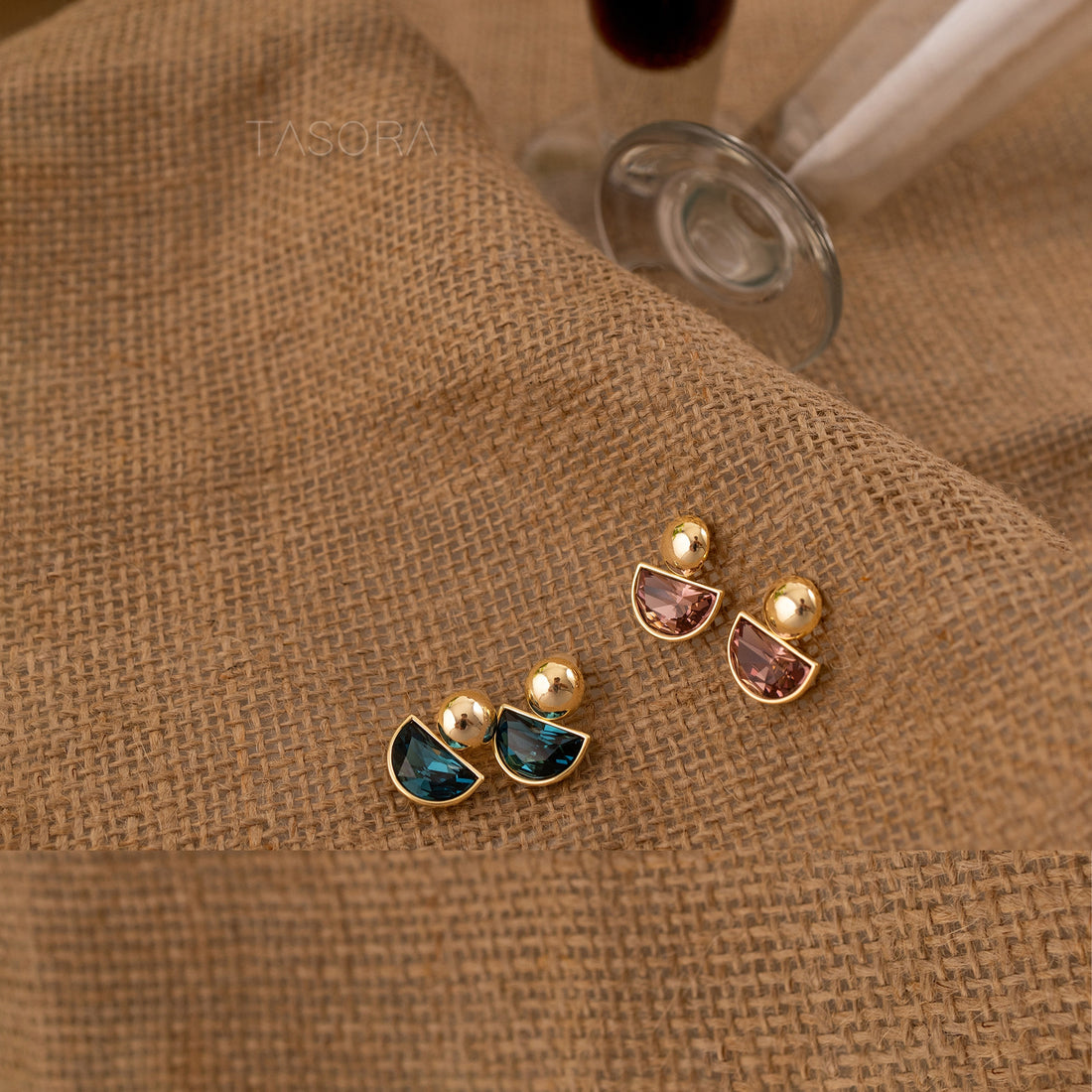 Pair of Minty Cove earrings with gemstone-like stones on a textured brown fabric background with TASORA branding