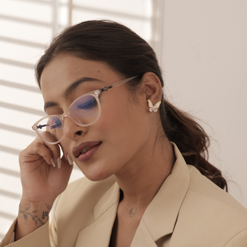 Woman wearing glasses, TASORA earrings and beige coat with a blurred background
