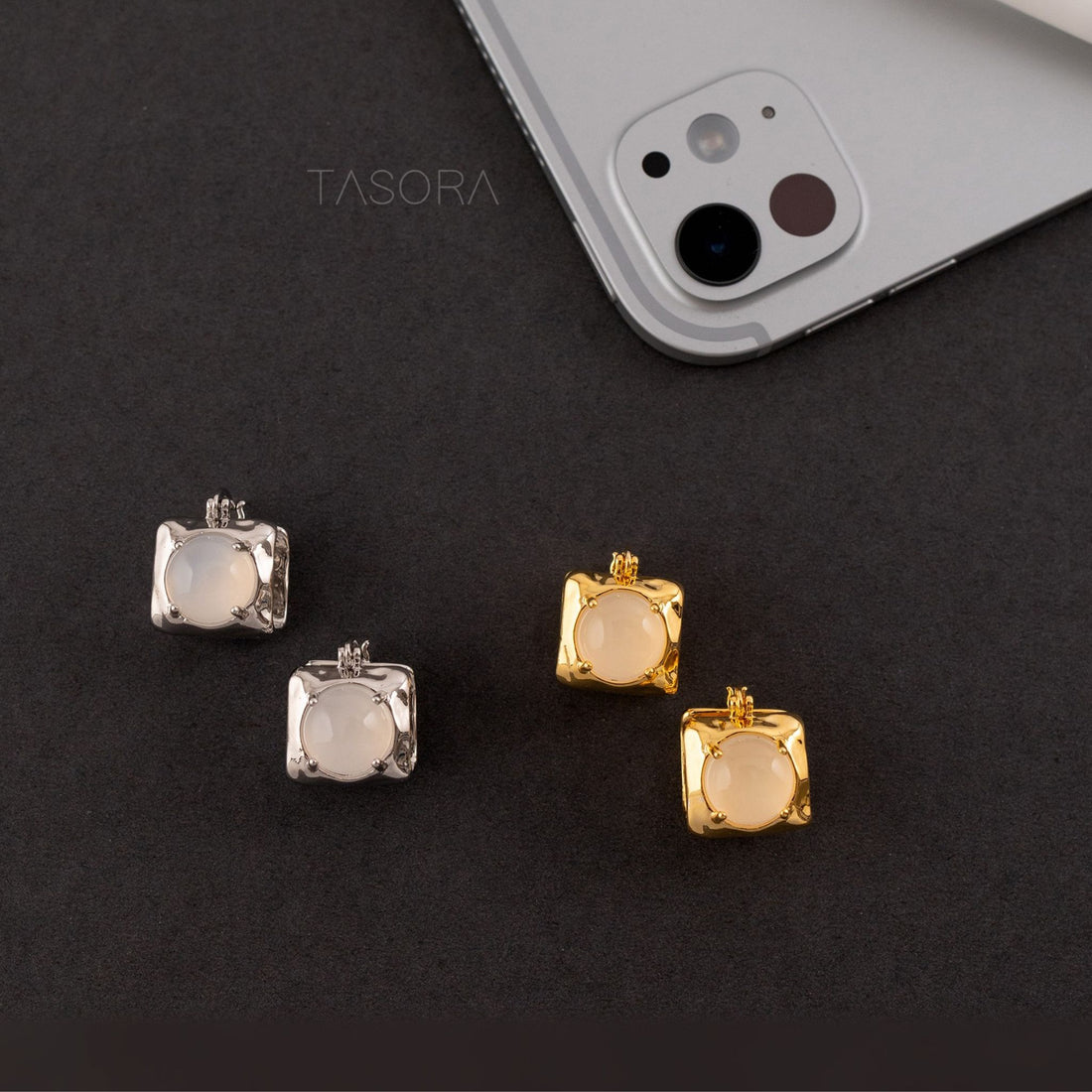 Square-Shaped Opaline Dot earrings in golden and silver on a dark surface with a phone in the background with TASORA branding.