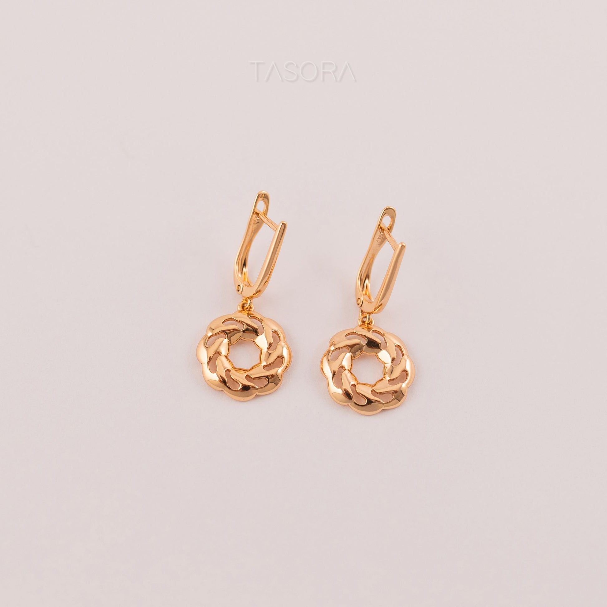 Pair of Orbbit Bloom golden earrings on a light gray background with 'TASORA' branding.