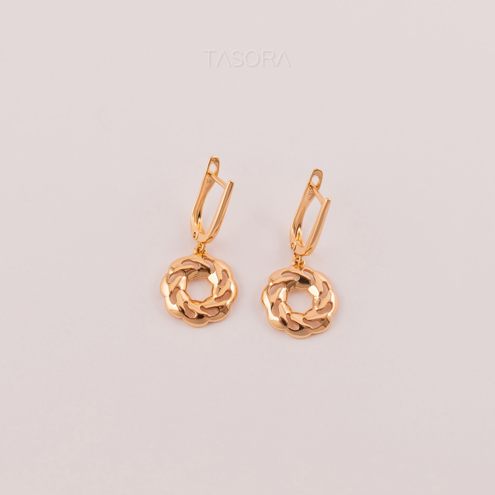 Pair of Orbbit Bloom golden earrings on a light gray background with 'TASORA' branding.