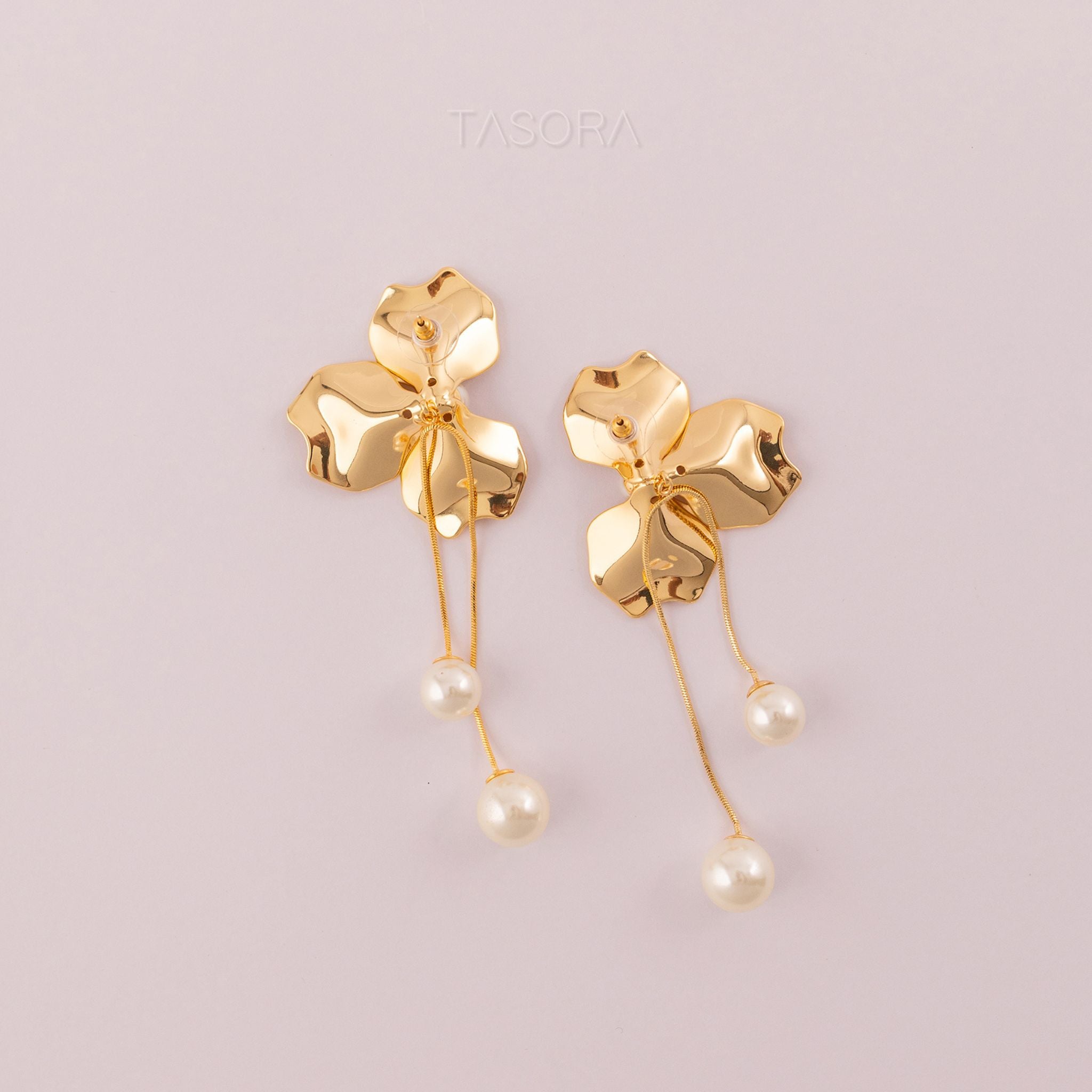 Back side of Orchid Pearls earrings with pearl drops on a light pink background with TASORA branding