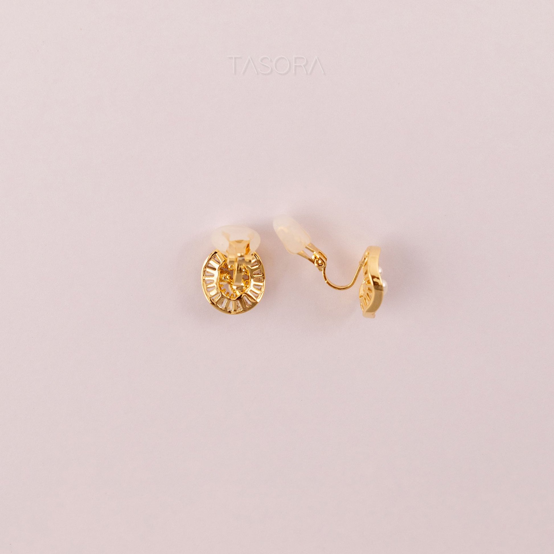 Back side of Oyster Muse Golden earrings on a light pink background with 'TASORA' branding.