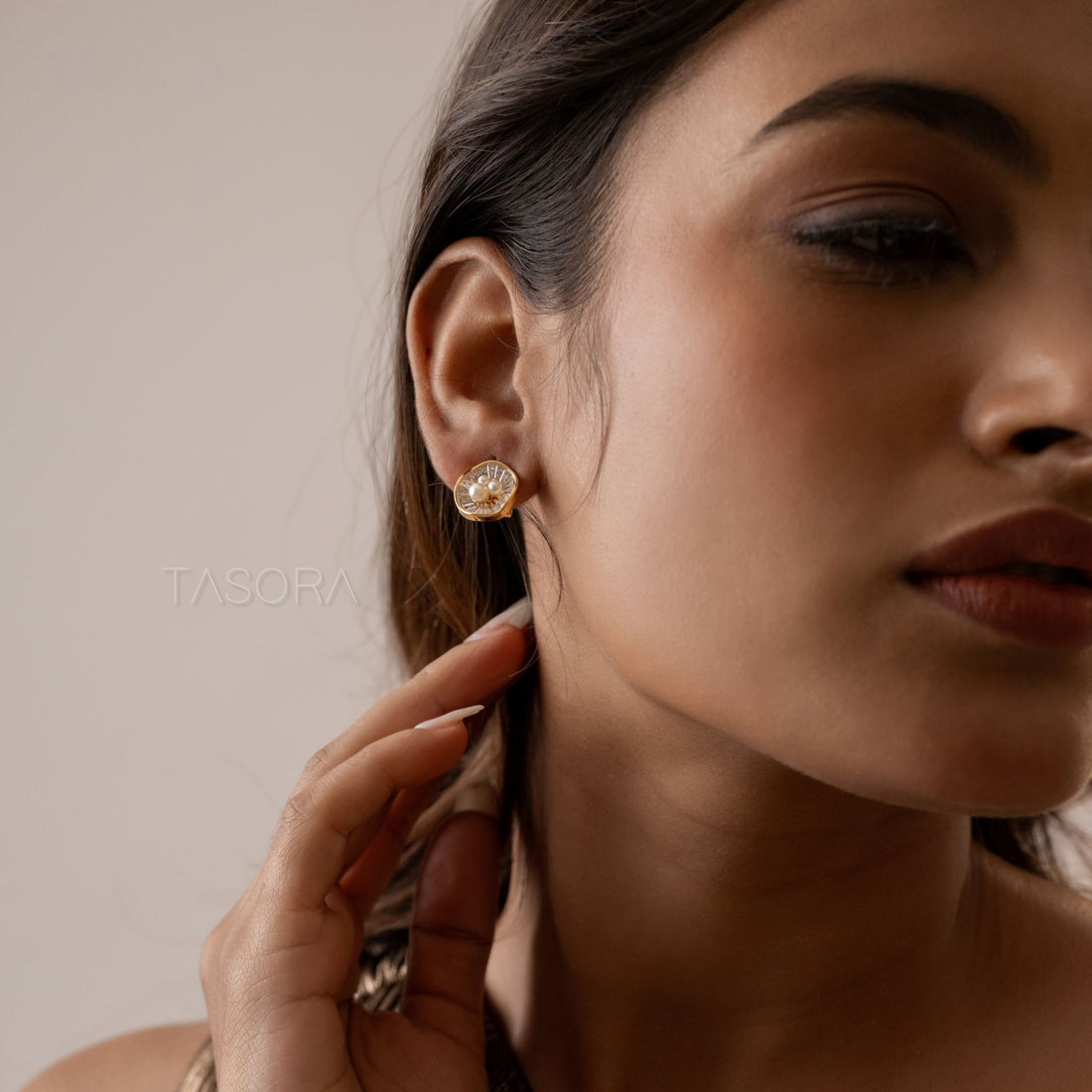 Gold and silver Oyster Muse earrings with pearls on a dark stone surface, TASORA brand visible.