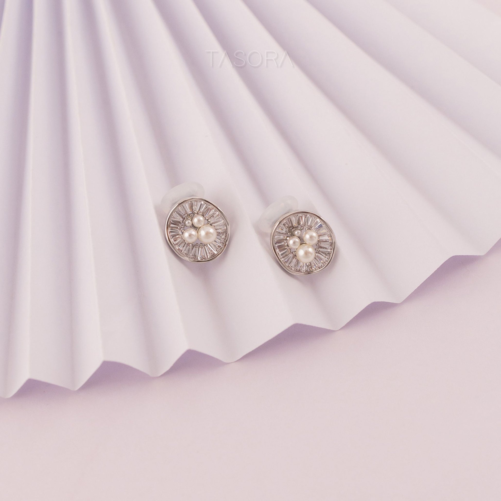 Pair of Oyster Muse silver earrings on a textured purple paper background with TASORA brand