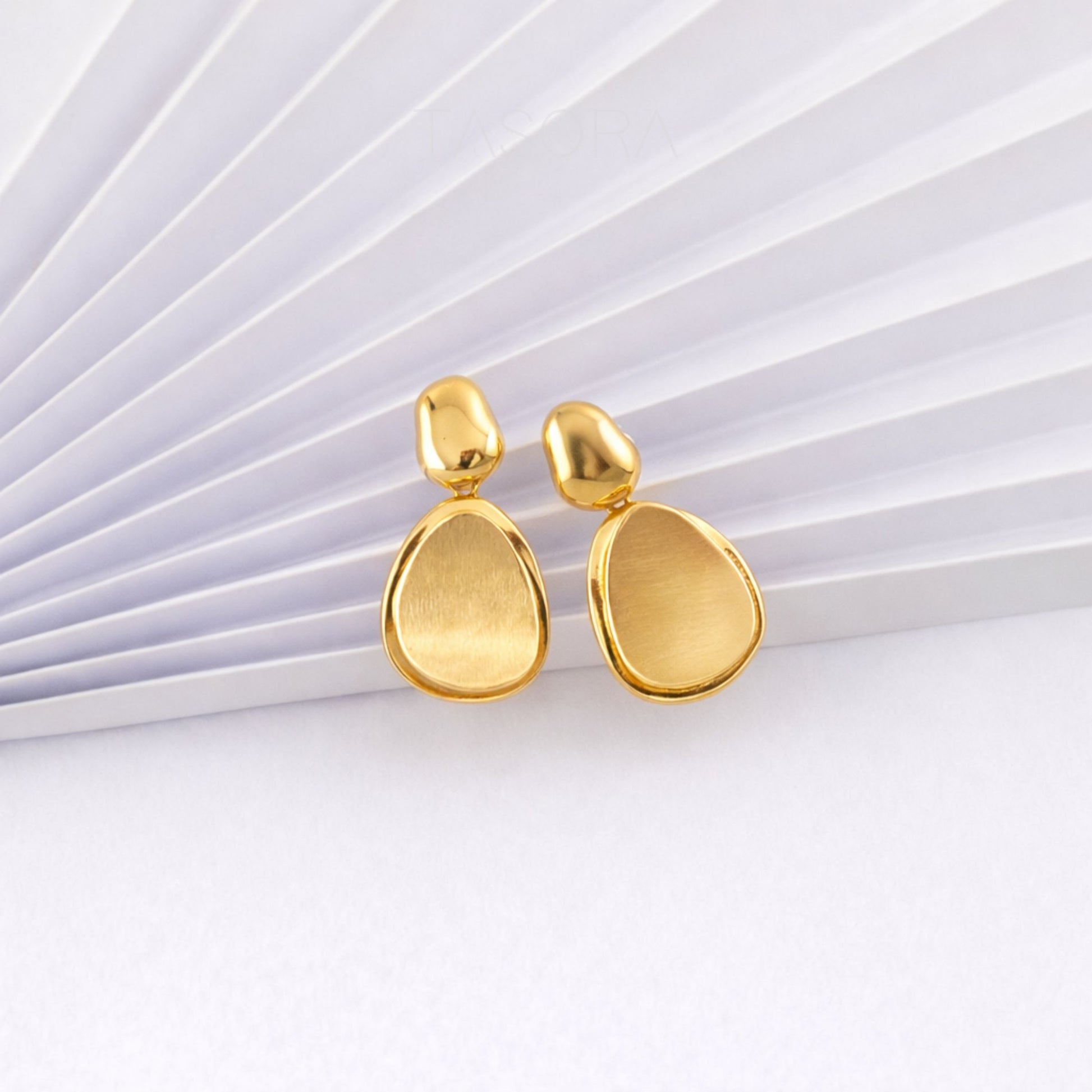 Gold teardrop earrings on a white background