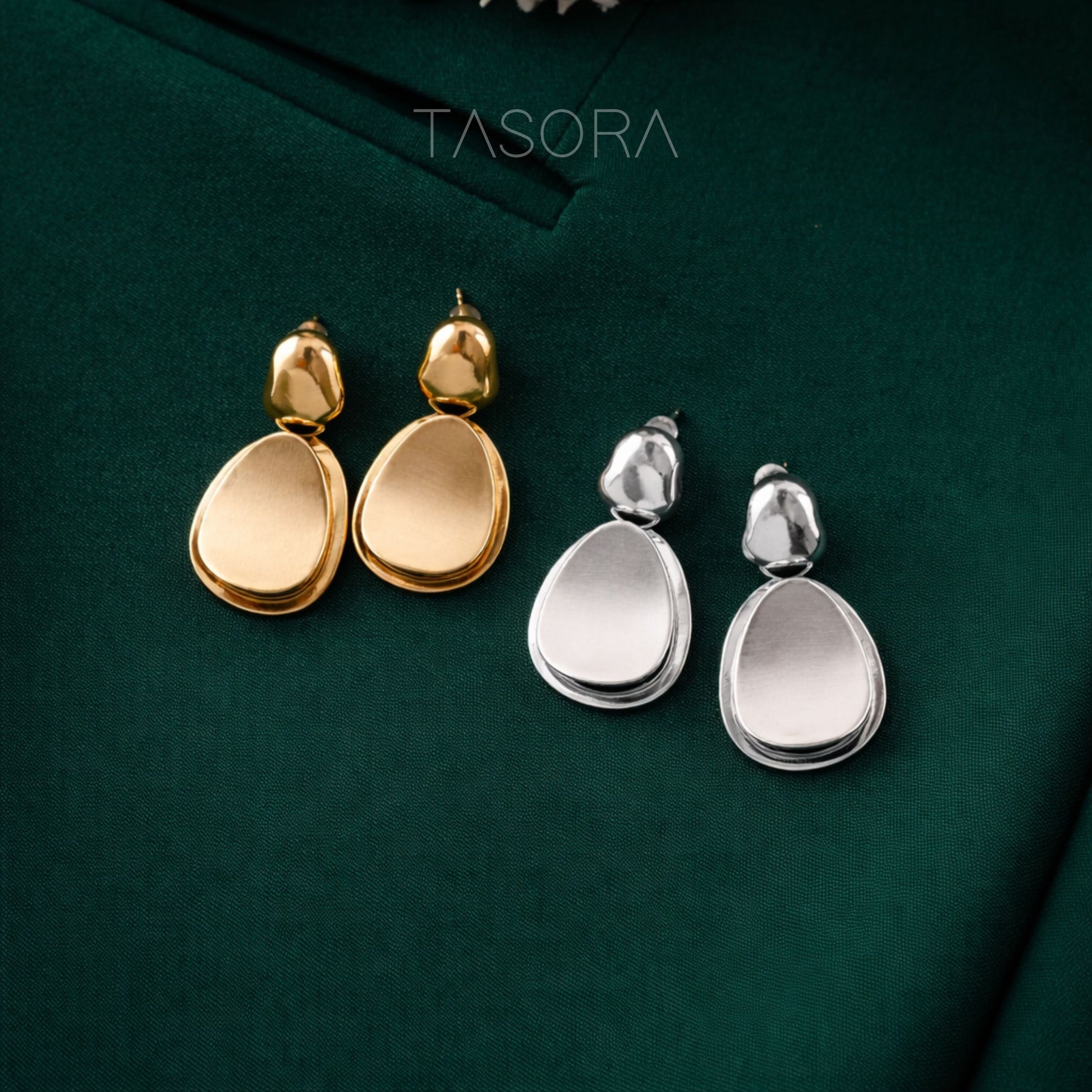 Gold and silver teardrop earrings on a green background with 'TASORA' branding.