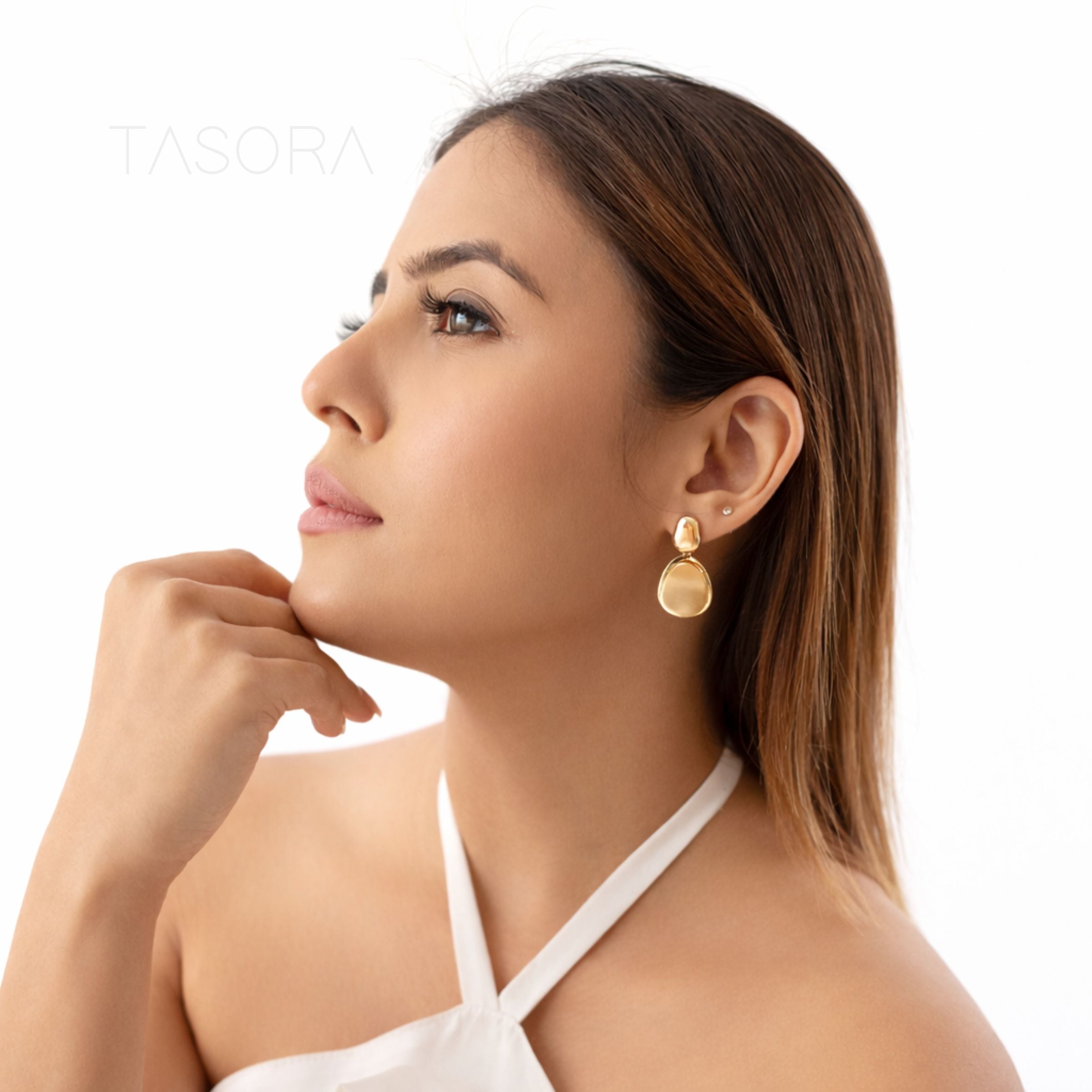 Woman wearing gold earrings with a white background 