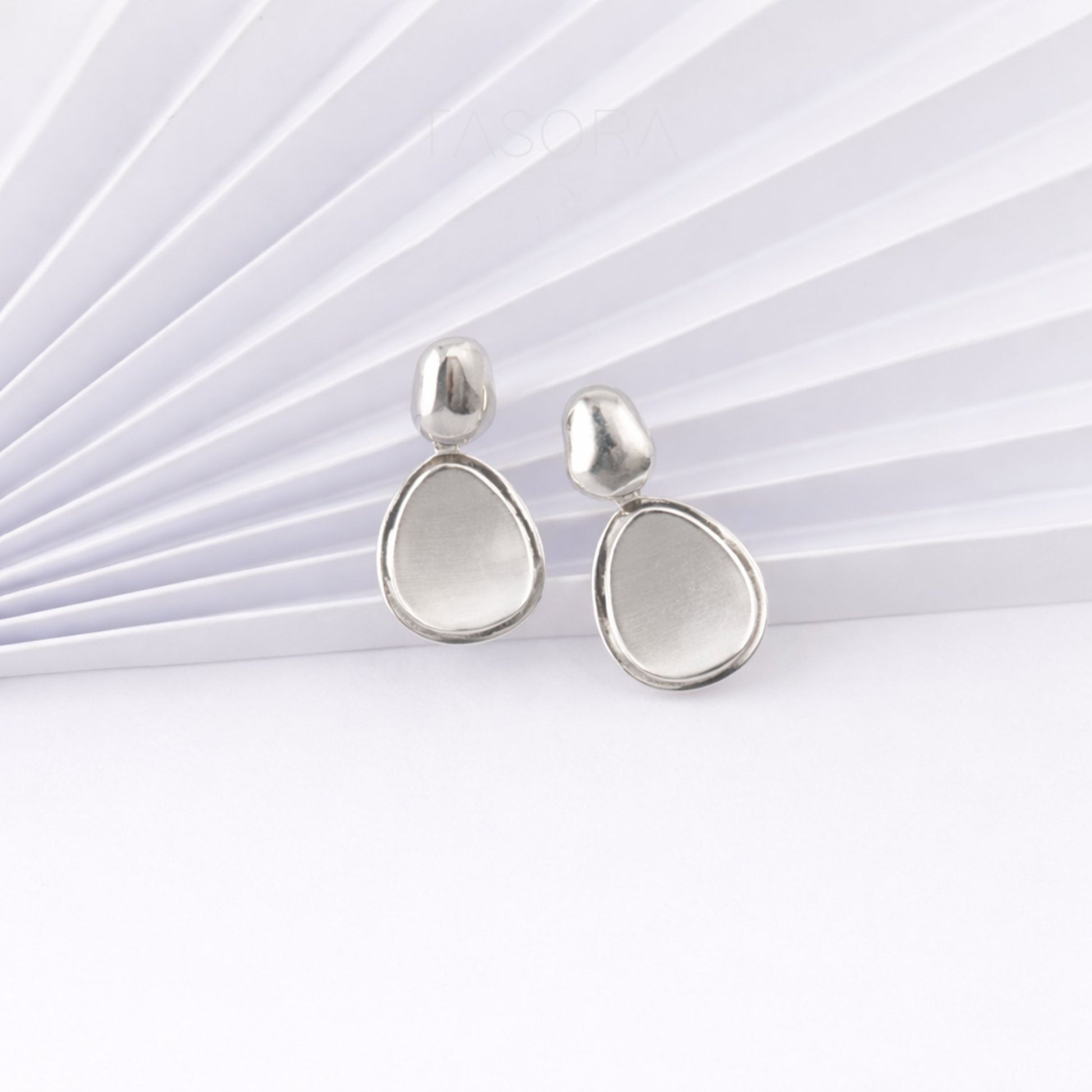 Pair of silver teardrop earrings on a white papert background