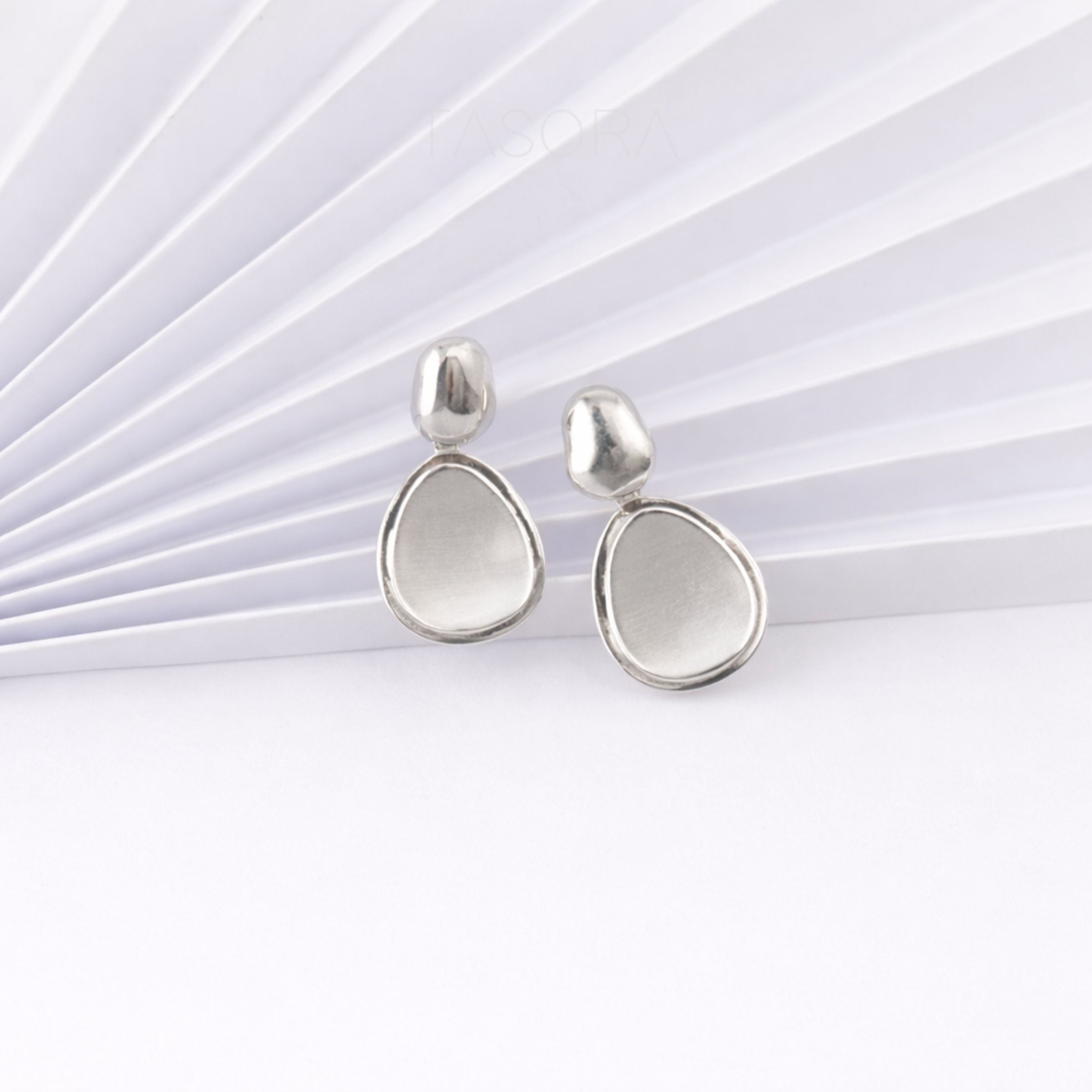 Pair of silver teardrop earrings on a white papert background