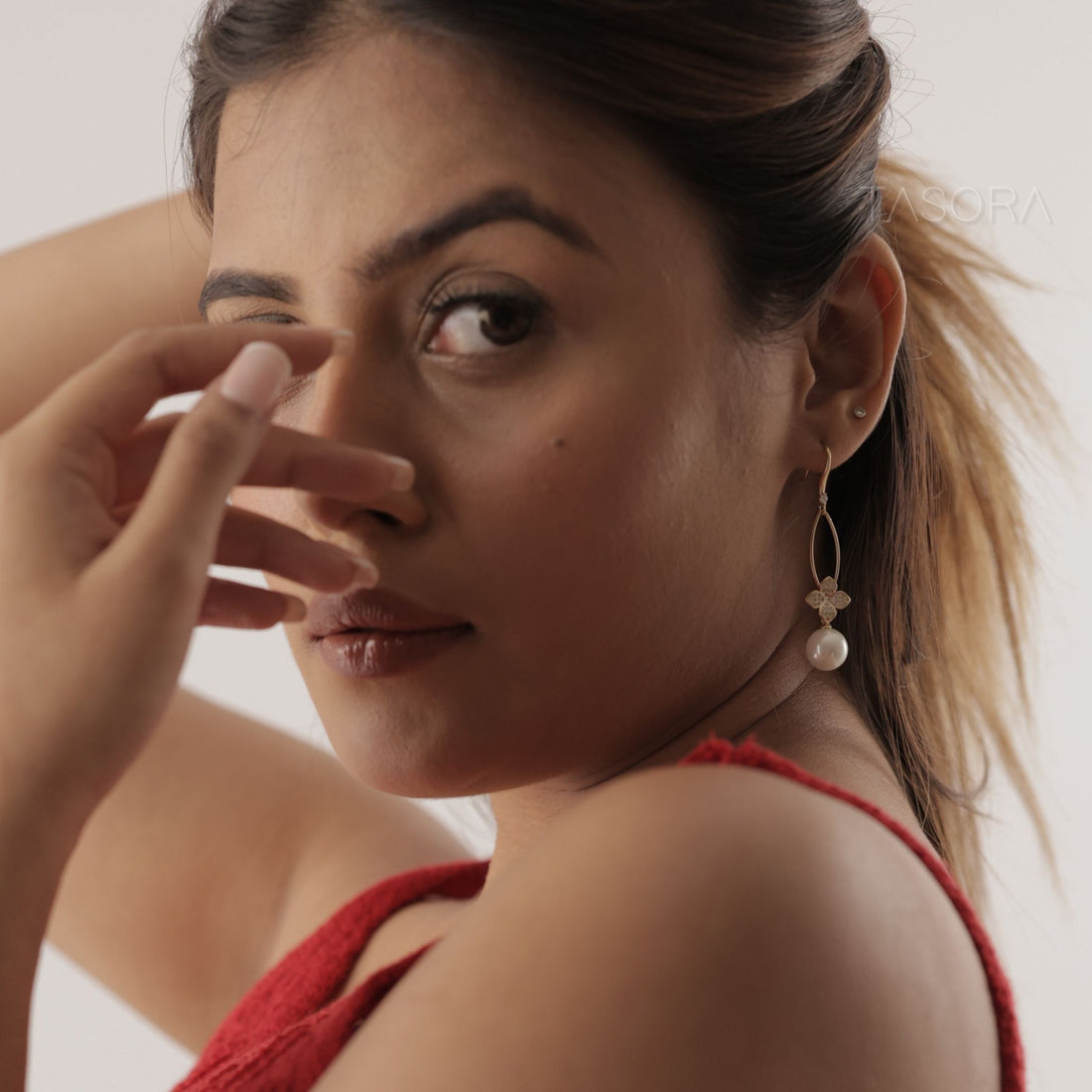 Golden Petal Fleur earrings with pearl drops on a branch against a dark background with TASORA branding