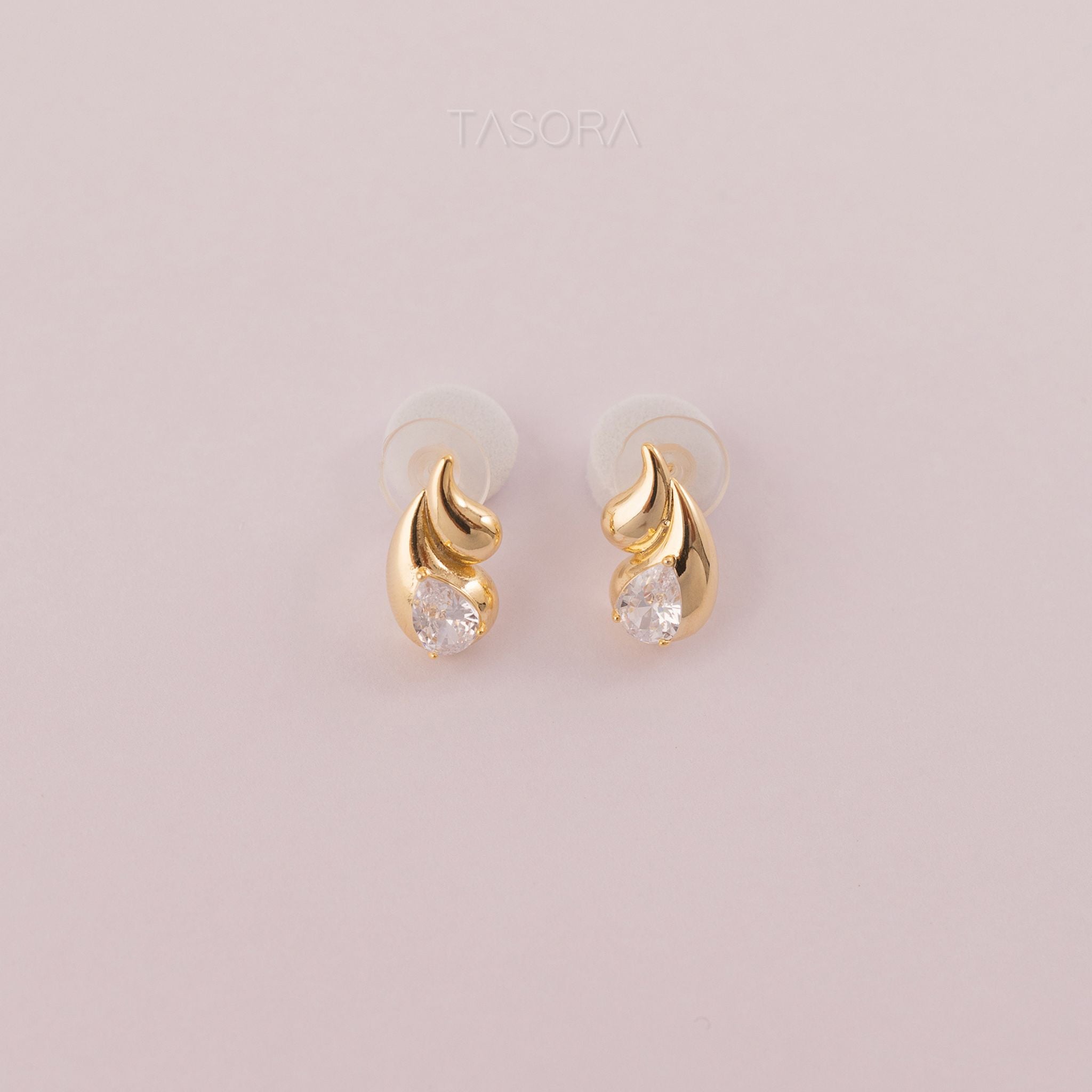 Rain Drop Golden earrings with clear stones on a light pink background with TASORA branding