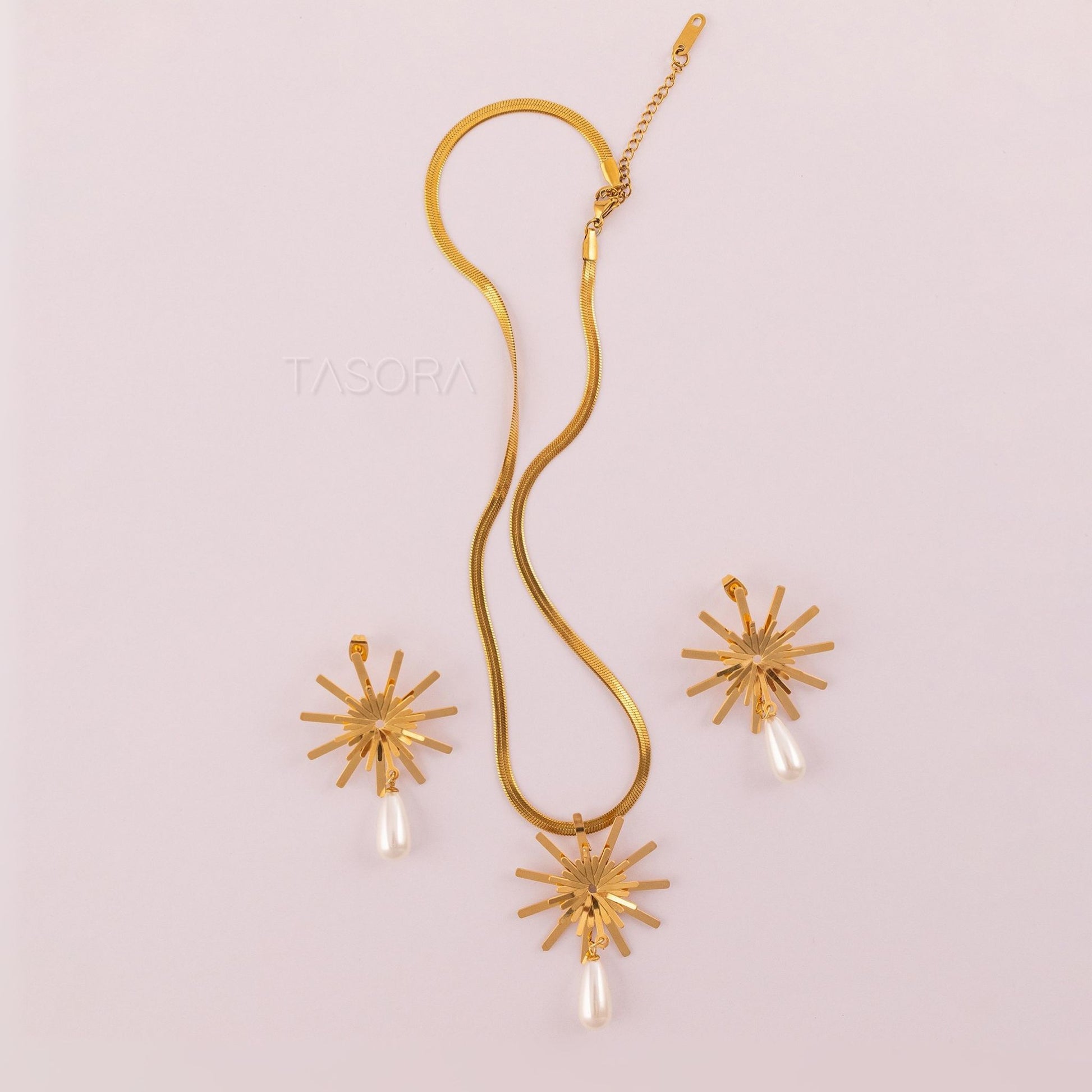 Golden Solara Bloom necklace and earrings set on a light pink background with 'TASORA' branding.