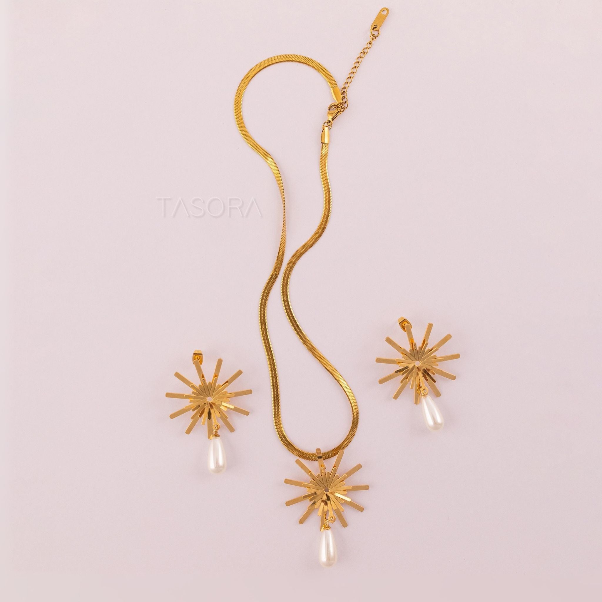Golden Solara Bloom necklace and earrings set on a light pink background with 'TASORA' branding.
