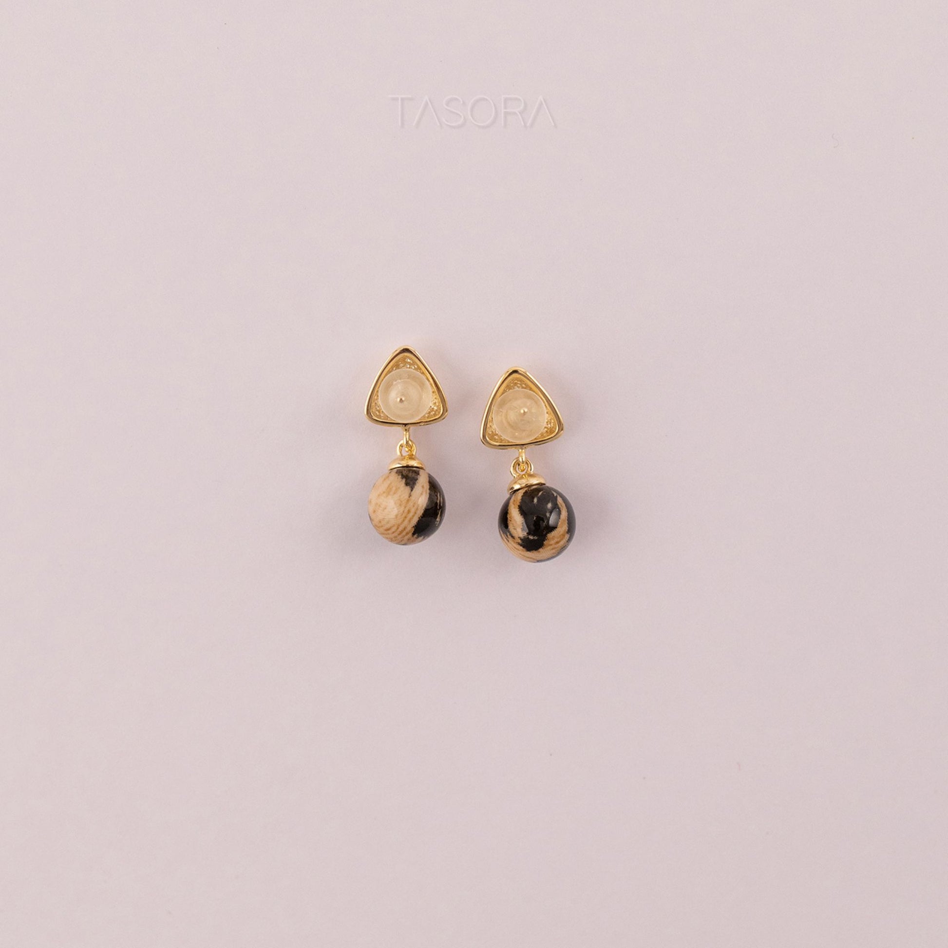 Back side of Sona Halo earrings with gold and black stones on a light pink background with TASORA branding