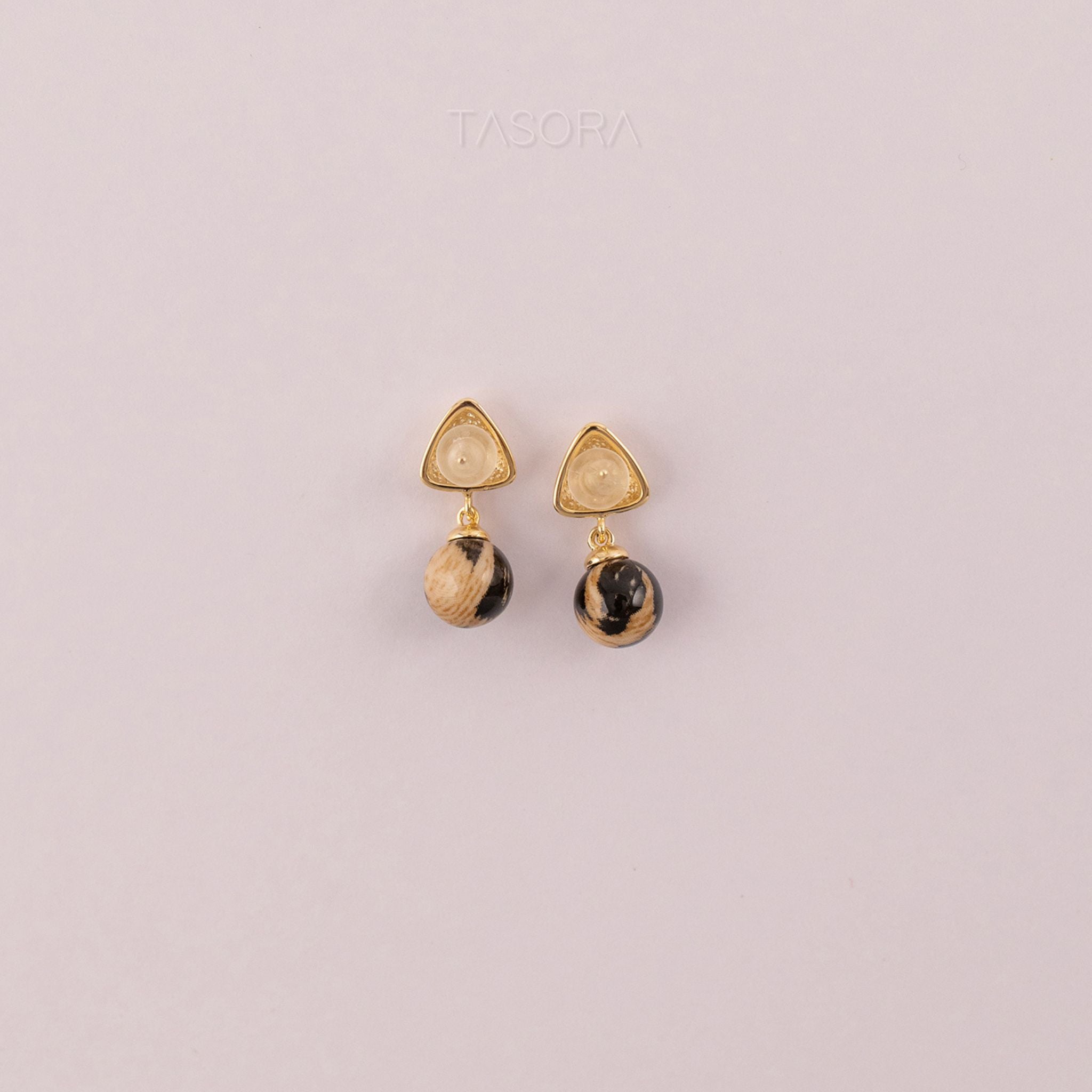 Back side of Sona Halo earrings with gold and black stones on a light pink background with TASORA branding