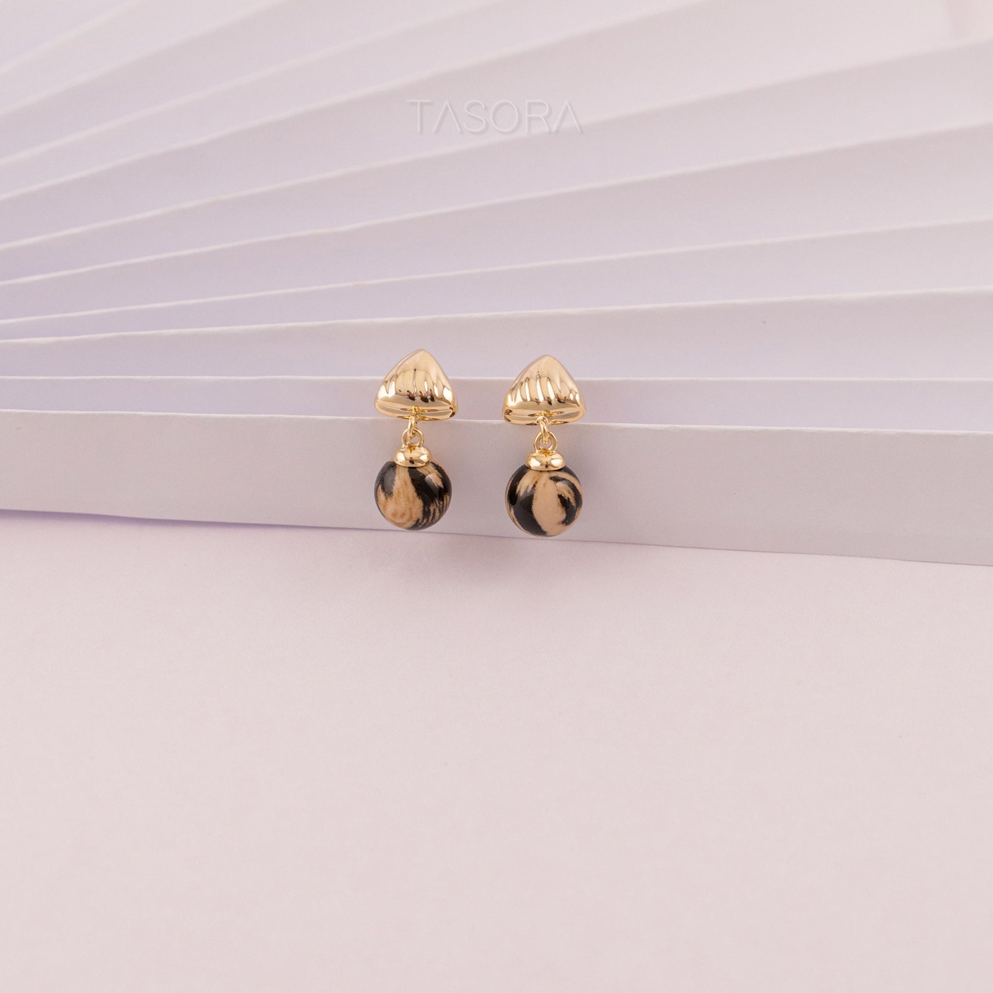 Sona Halo Biege earrings with black accents on a white paper surface with TASORA branding