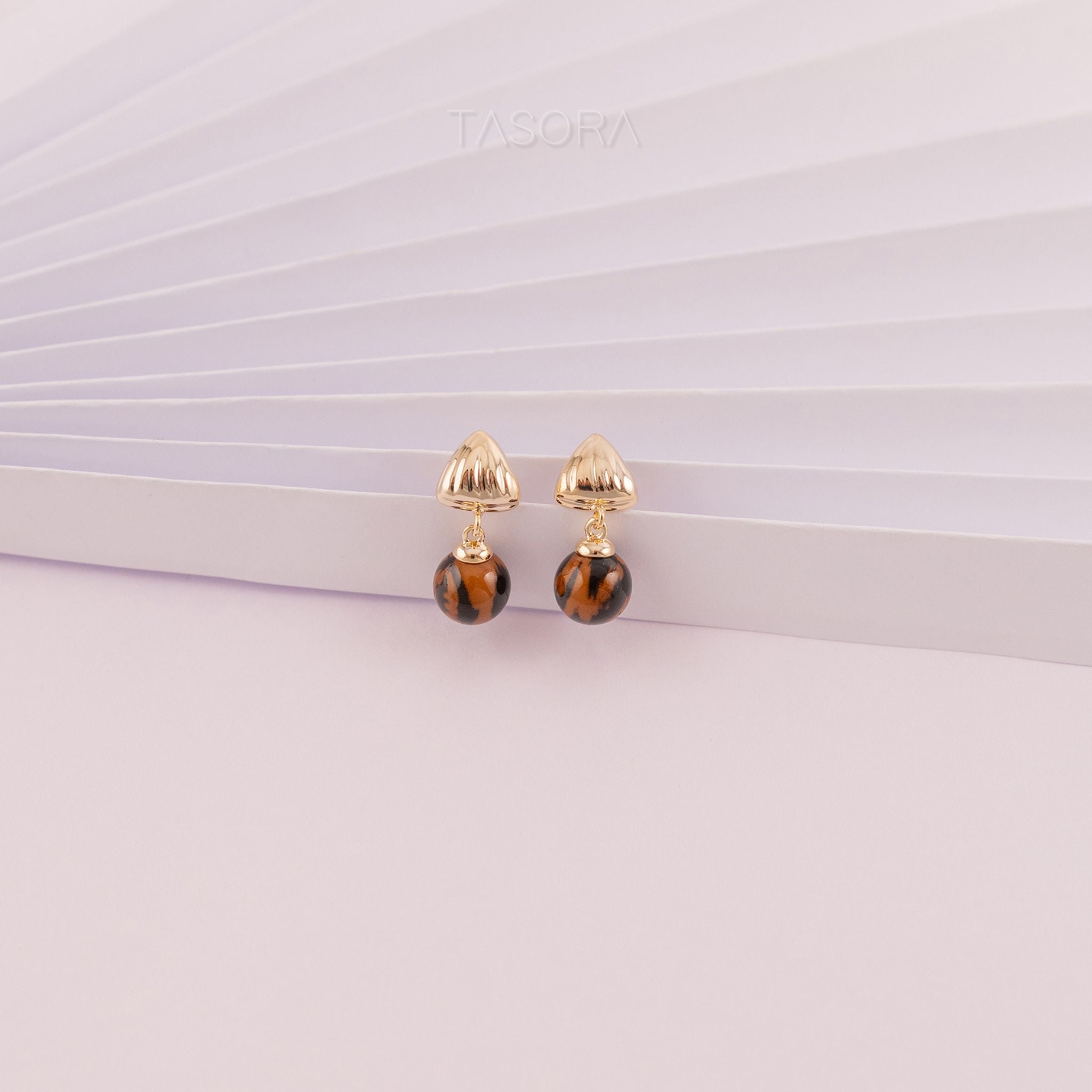 Pair of Sona Halo earrings with tortoiseshell beads on a light texture background with TASORA branding