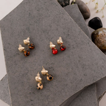 Pairs of Sona Halo earrings of TASORA brand on a gray stone surface.