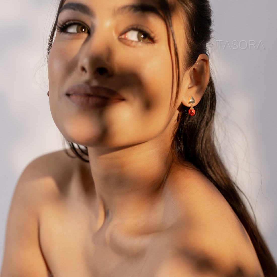 Pairs of Sona Halo earrings of TASORA brand on a gray stone surface.