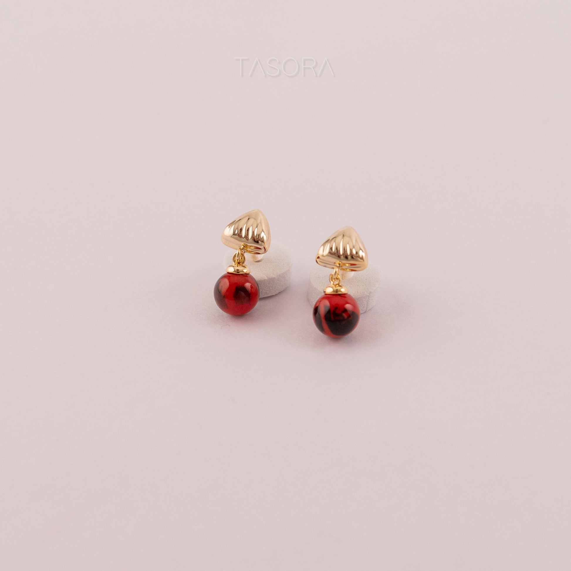 Gold and red Sona Halo earrings on a light pink background with TASORA branding