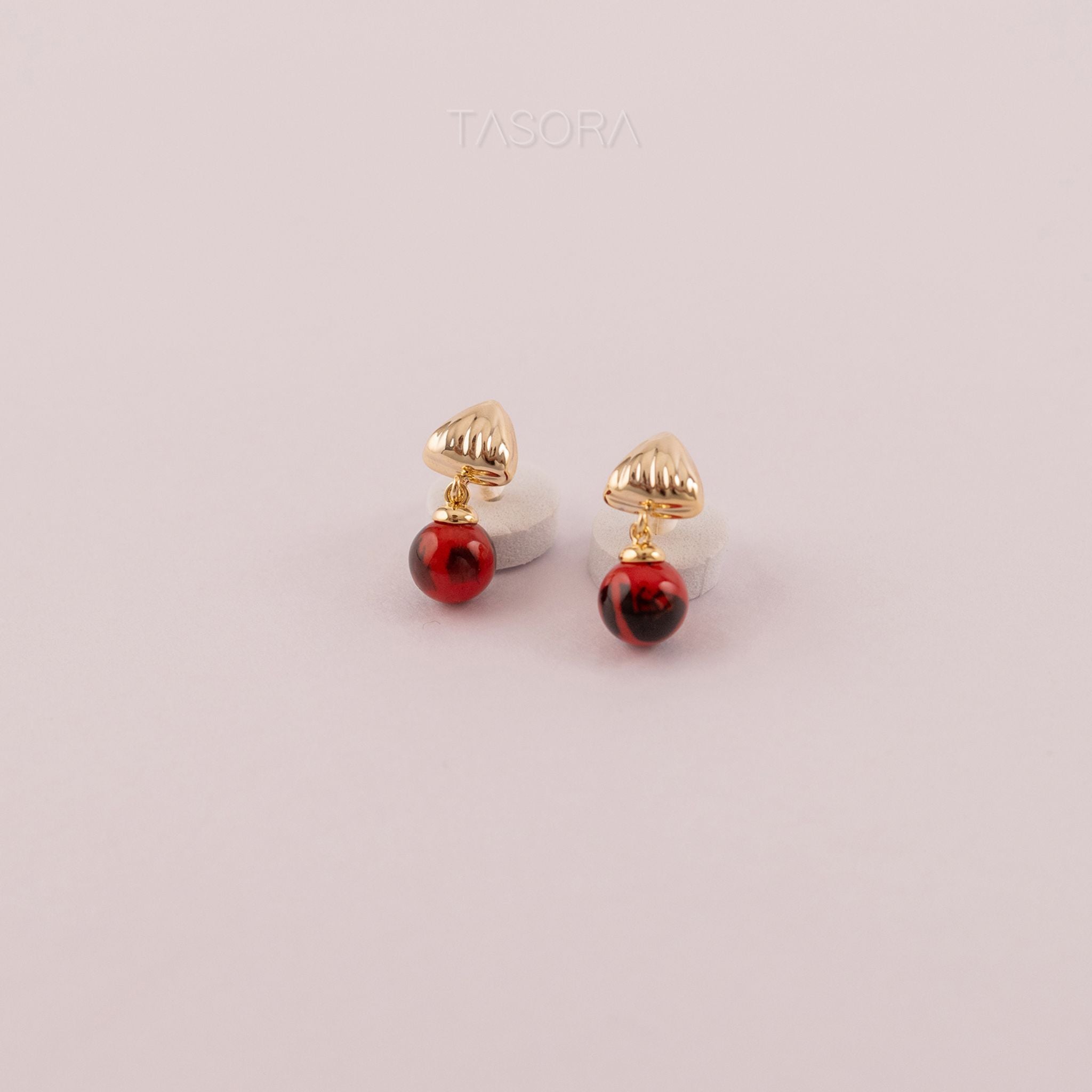Gold and red Sona Halo earrings on a light pink background with TASORA branding