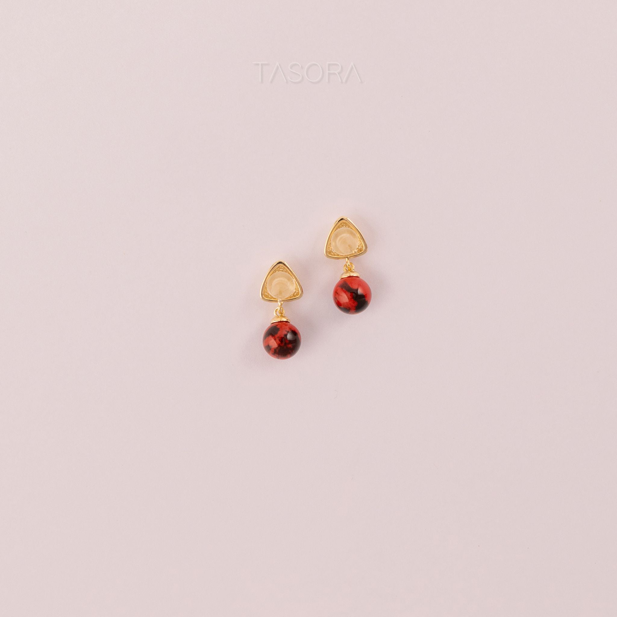 Back side of Sona Halo earrings gold and red colour on a light pink background with 'TASORA' branding.