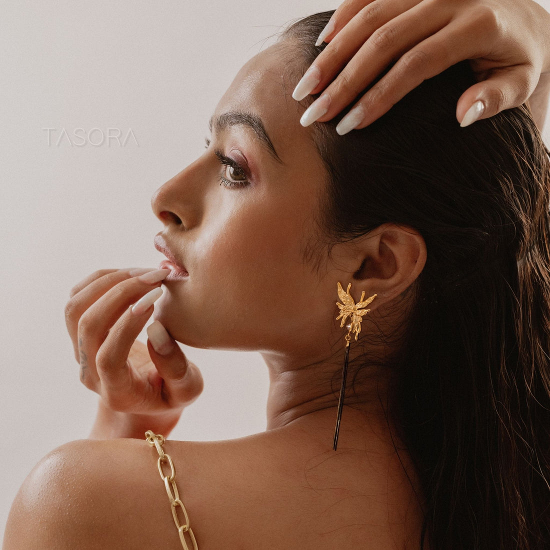 Zalfi Tassels Golden earrings with tassels on a textured surface, branded 'TASORA'.