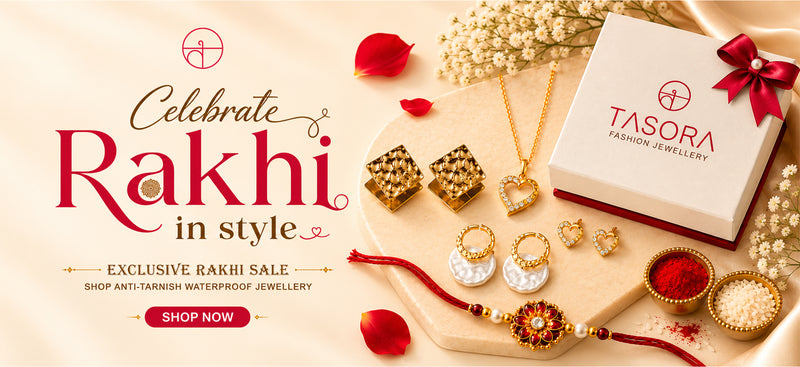A festive promotional banner for Tasora Fashion Jewellery featuring a Rakhi sale. The image displays various gold and silver-toned jewelry items, including necklaces, earrings, and a gold-plated Rakhi, arranged on a decorated wooden board with red powder, rose petals, and a white Tasora gift box.